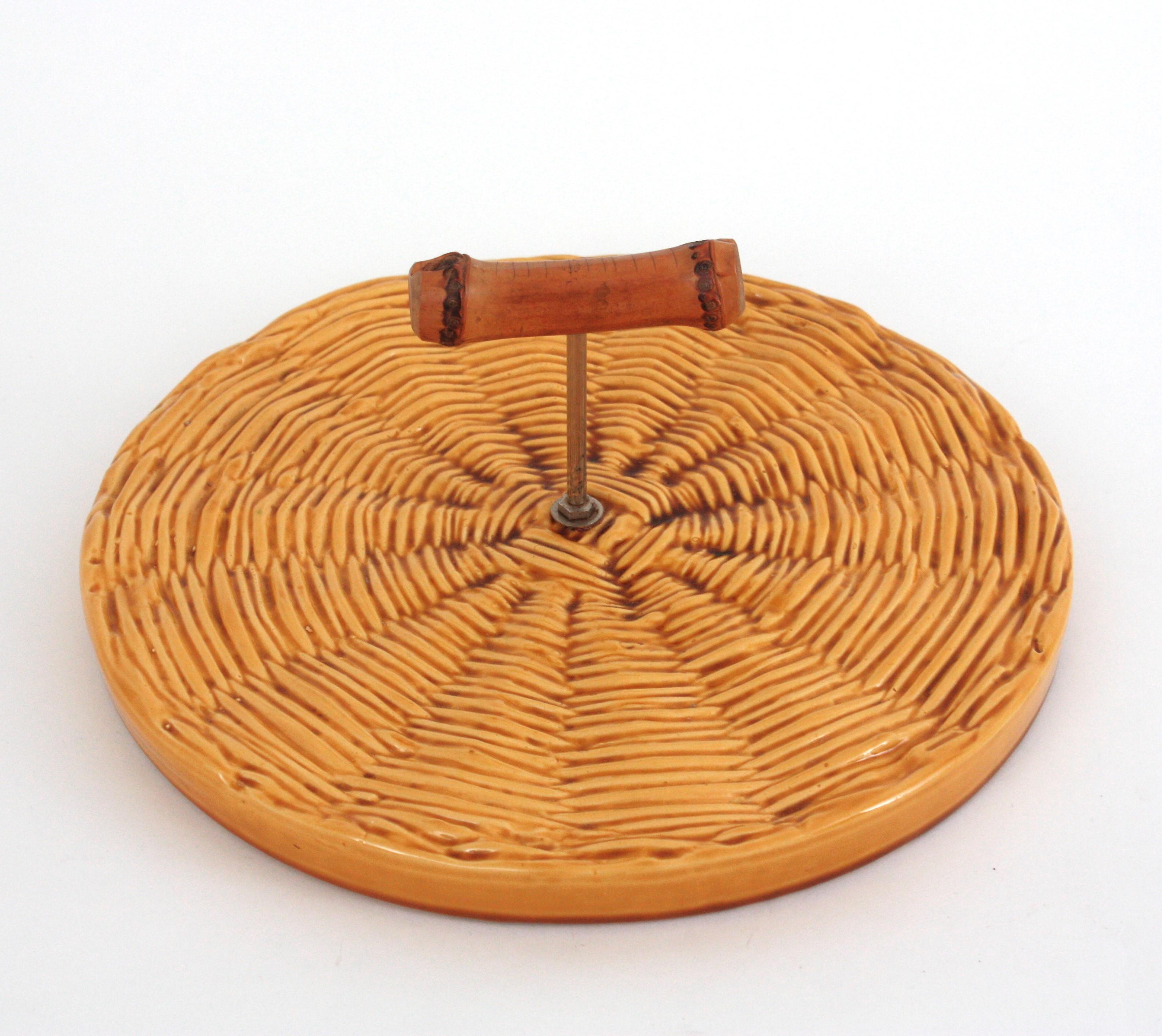 Fresca fuente de cerámica con motivo tejido y forma redonda para quesos o postres, Francia, años 50.
Esta hermosa fuente tiene una base circular con motivos tejidos. Un asa en la parte central con un tirador de bambú permite transportarla