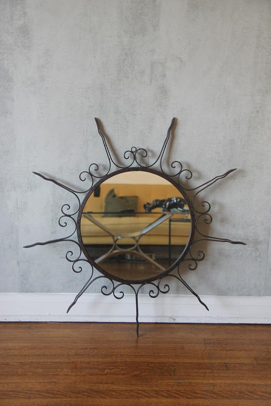 Questo splendido specchio francese in ferro battuto a raggiera risale agli anni '50 e mostra una squisita lavorazione artigianale. Lo specchio presenta un design di grande impatto con raggi che si irradiano con eleganza, realizzati in ferro laccato
