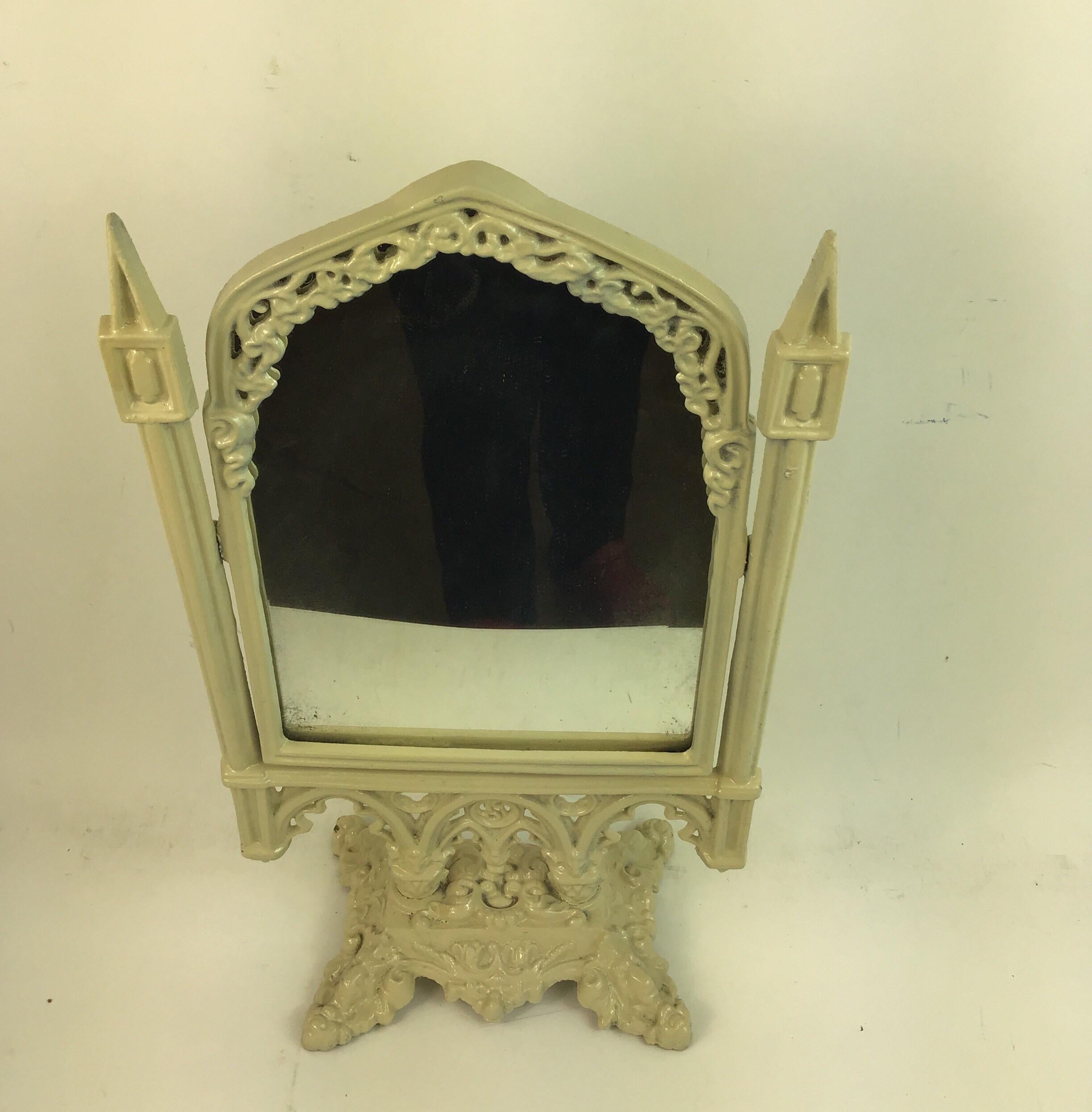 Vanity mirror in cast metal with crème paint finish.