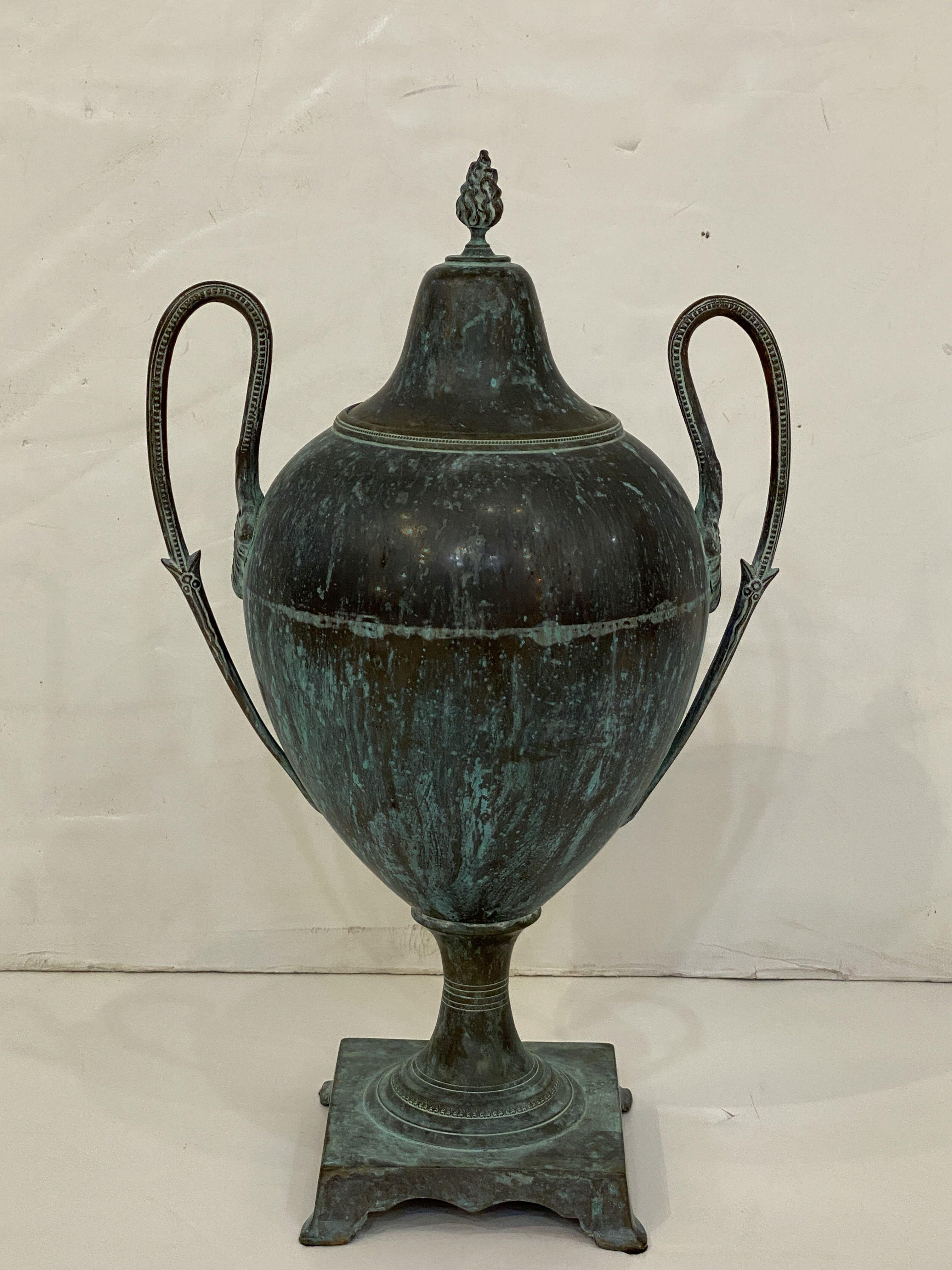 A fine French decorative urn or vase of copper in the Classical style, with a beautiful verdigris patina over the whole, featuring a removable lid with finial, fitted to an urn body with two opposing handles, and resting on a square