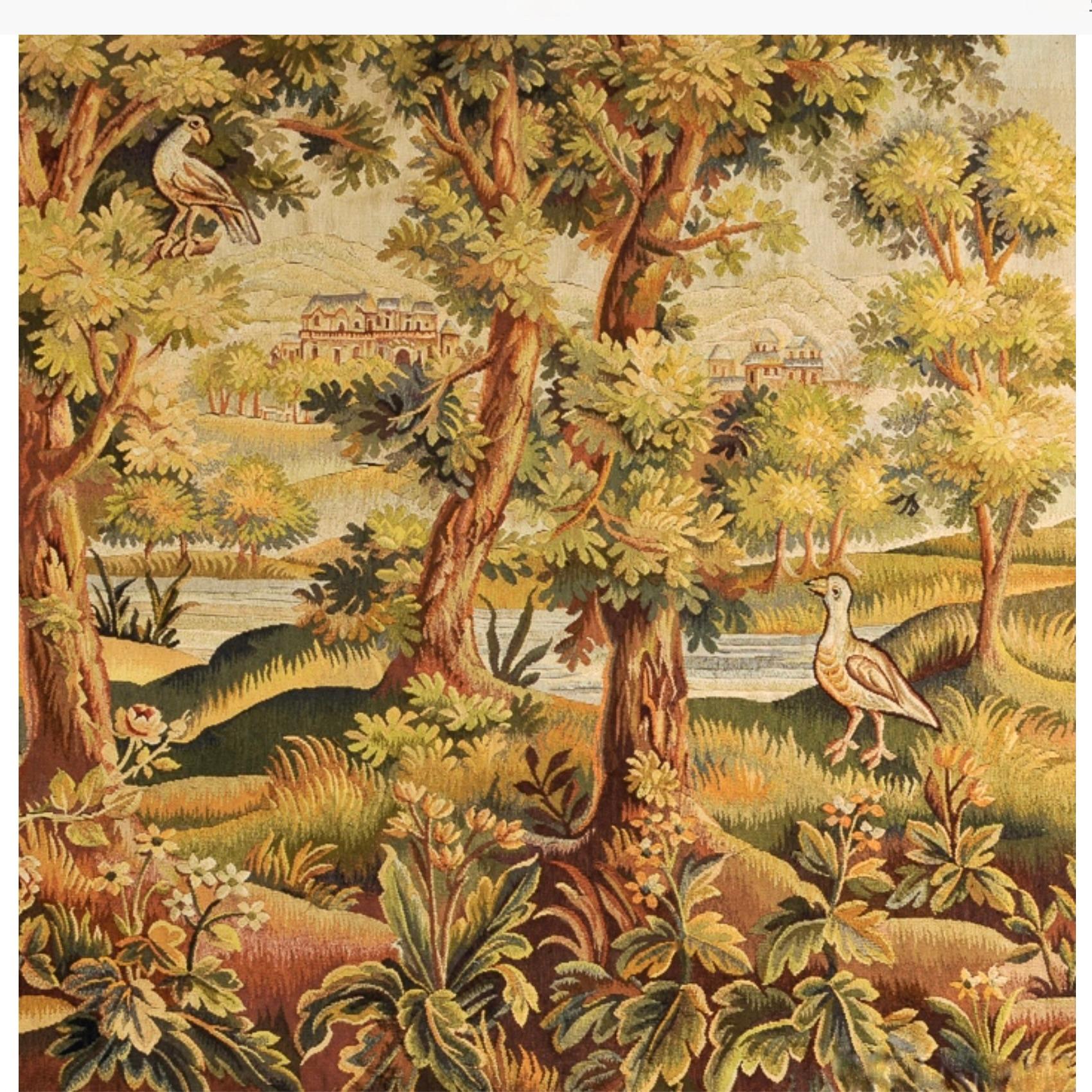 A fine landscape tapestry executed in wool and silk, depicting a leafy view over a river bank through large trees to a clearing beyond containing two castle vignettes. Dark blue/black borders frame the scene simply and attractively. The tapestry is
