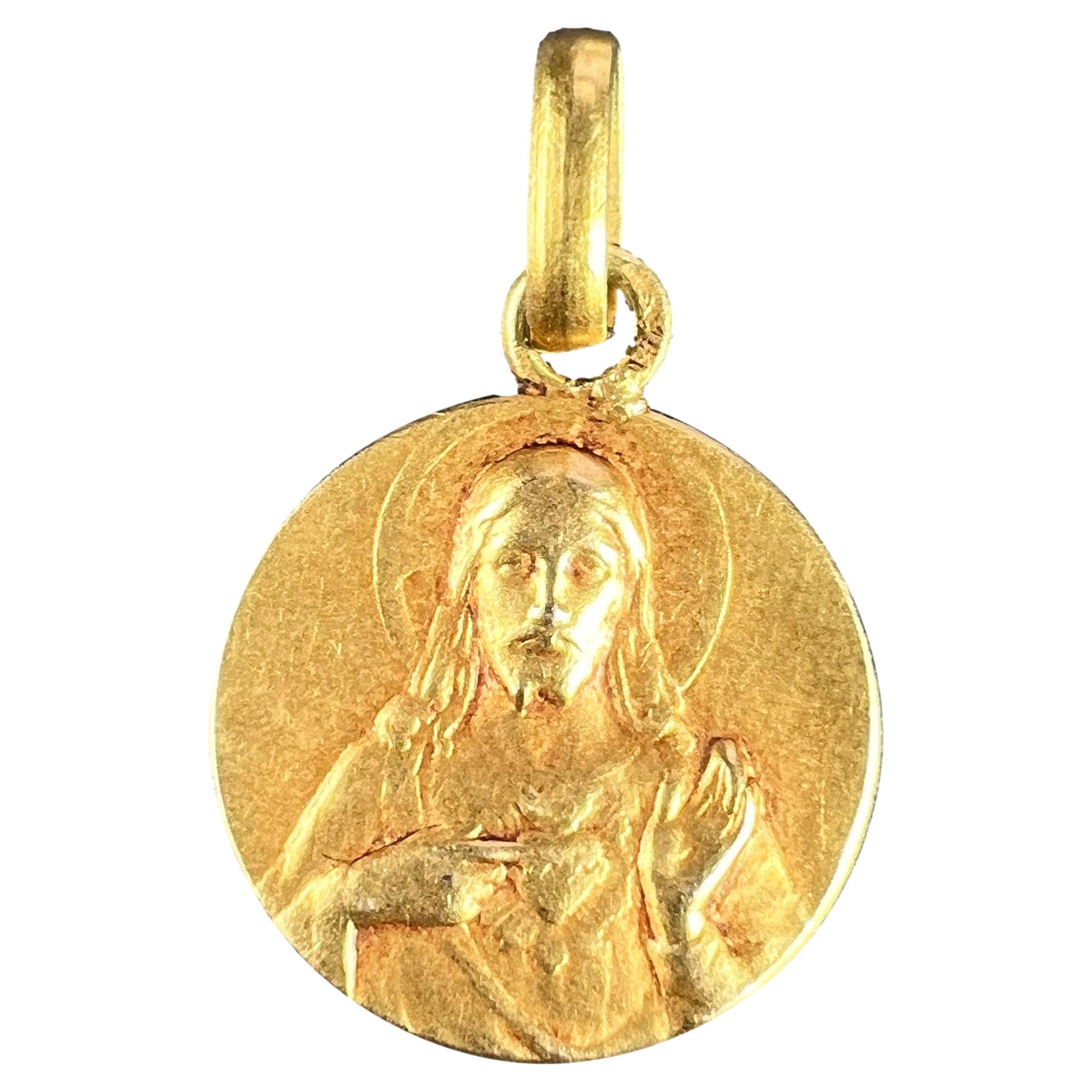 A French 18 karat (18K) yellow gold charm pendant designed as an oval medal depicting the Madonna and Child, signed Vern. The reverse depicts a bunch of roses and lilies and is engraved with the name Gabrielle and the date '17 Septembre 1909'.