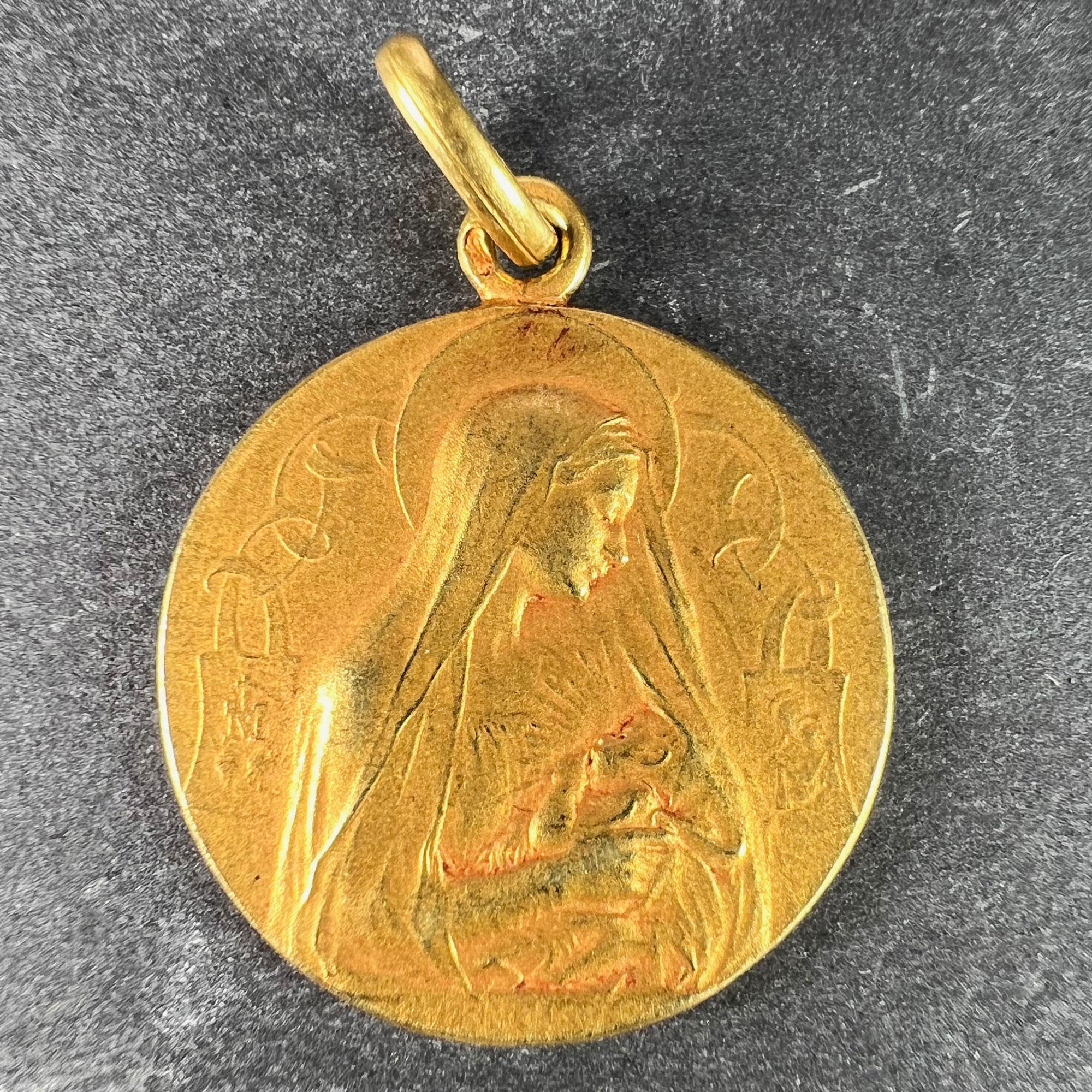 A French 18 karat (18K) yellow gold charm pendant designed as a round medal with a relief of Jesus Christ with the Sacred Heart to one side, to the other the Virgin Mary as Madonna and Child, with the Marian symbol to one side. Signed F. Vernon to