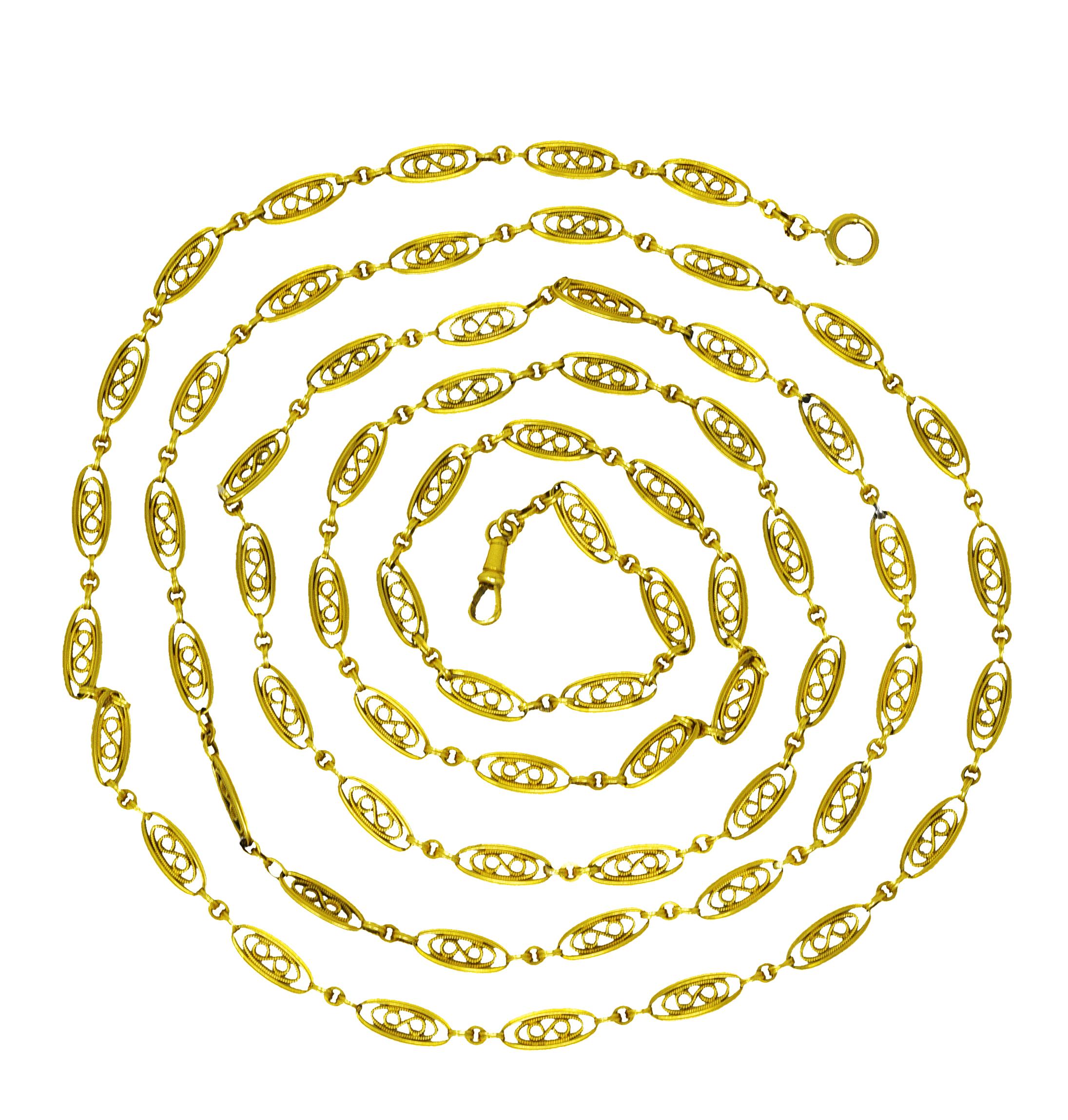 Long chain necklace is comprised of oval links - deeply ridged. And centering scrolled filigree with a milgrain texture. Alternating with ridged and circular spacer links. Terminating as an antique lobster bale. And spring ring clasp closure. With