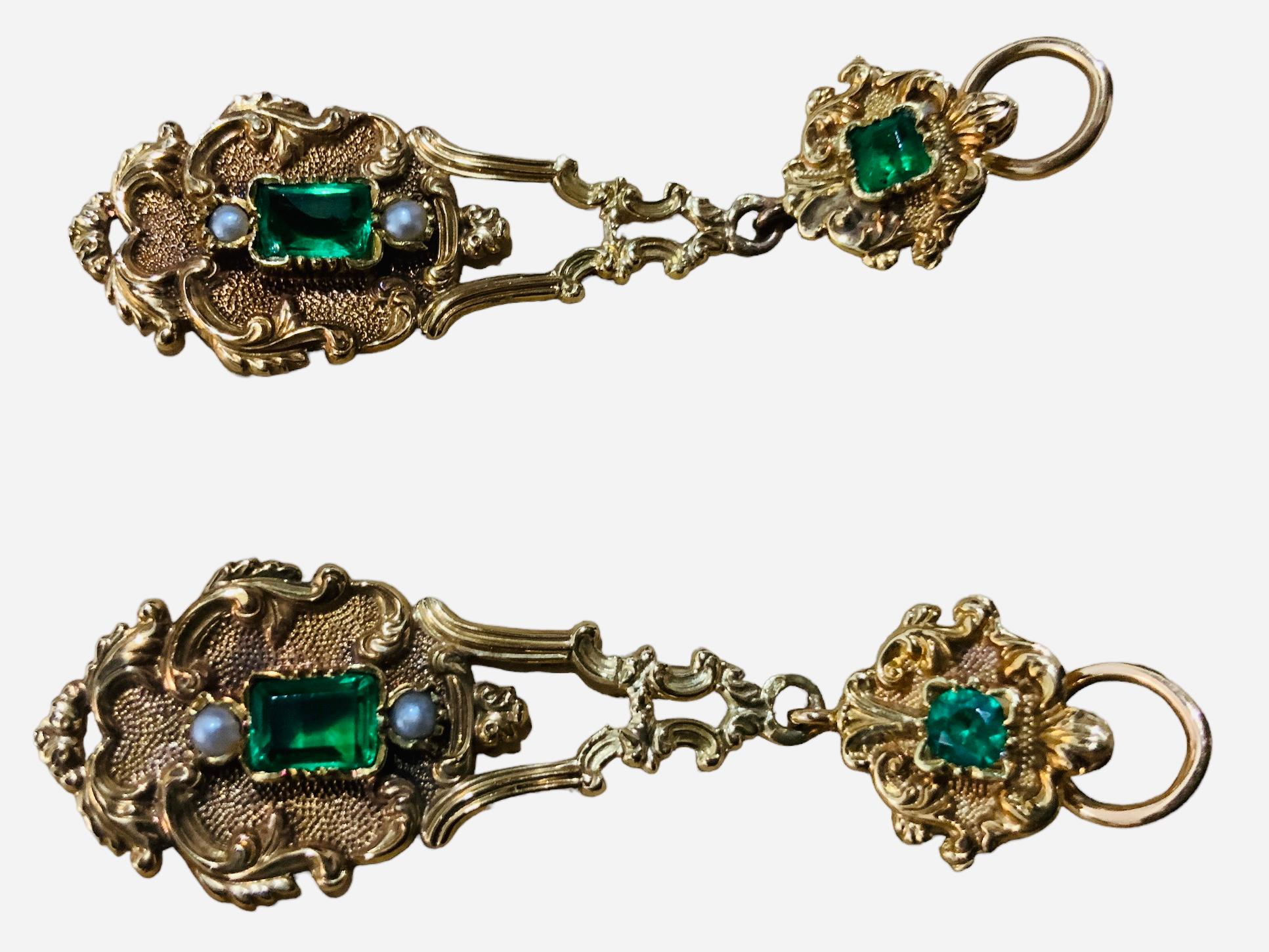 Dies ist eine viktorianische 18K Gold und grünem Glas Paar Tropfen Ohrringe. Es zeigt zwei grüne Gläser im Smaragdschliff, das untere größer als das obere, umgeben von blumigen Details aus 18 K Gelbgold und Akanthusblättern. Zwei Saatperlen