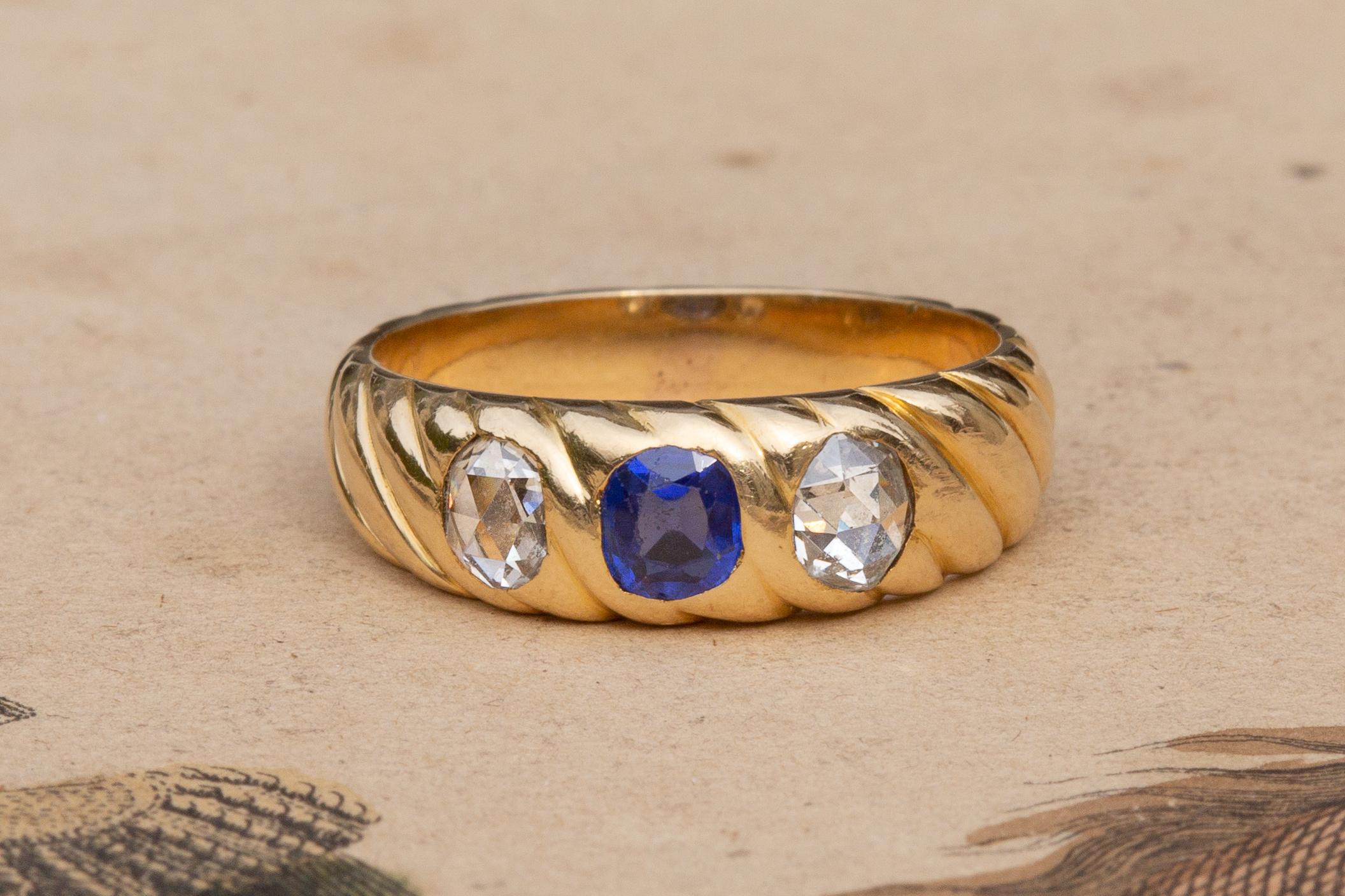 Stunning Victorian Heavy 18K Gold Sapphire and Diamond Trilogy Ring

A unique French heavy gold three stone ring dating to the late 19th century, circa 1890. The twisted and tapered rope hoop is beautifully crafted in 18K gold and features a vibrant