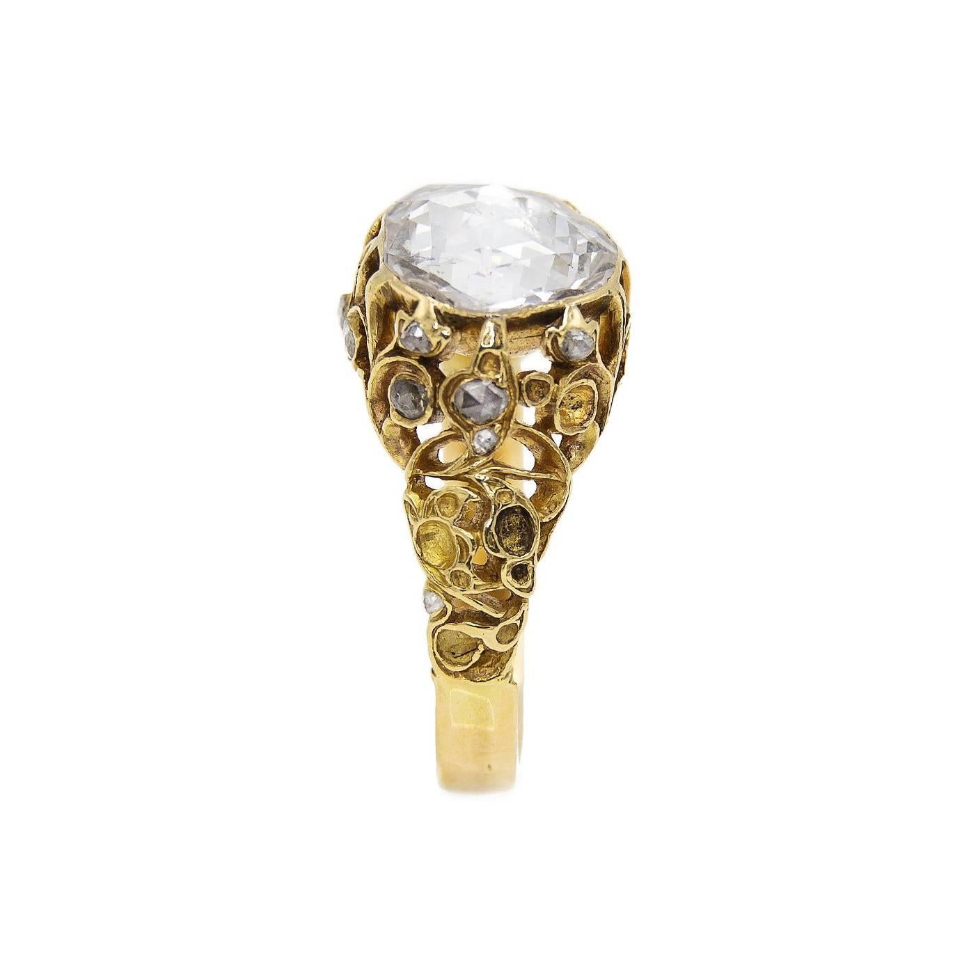  It has delicately floral carvings that hold this stunning diamond in place sprinkled with a multitude of accent diamonds. The center diamond is approximately 2.7 carats. This ring is from the French Victorian era of romance and opulence. It is