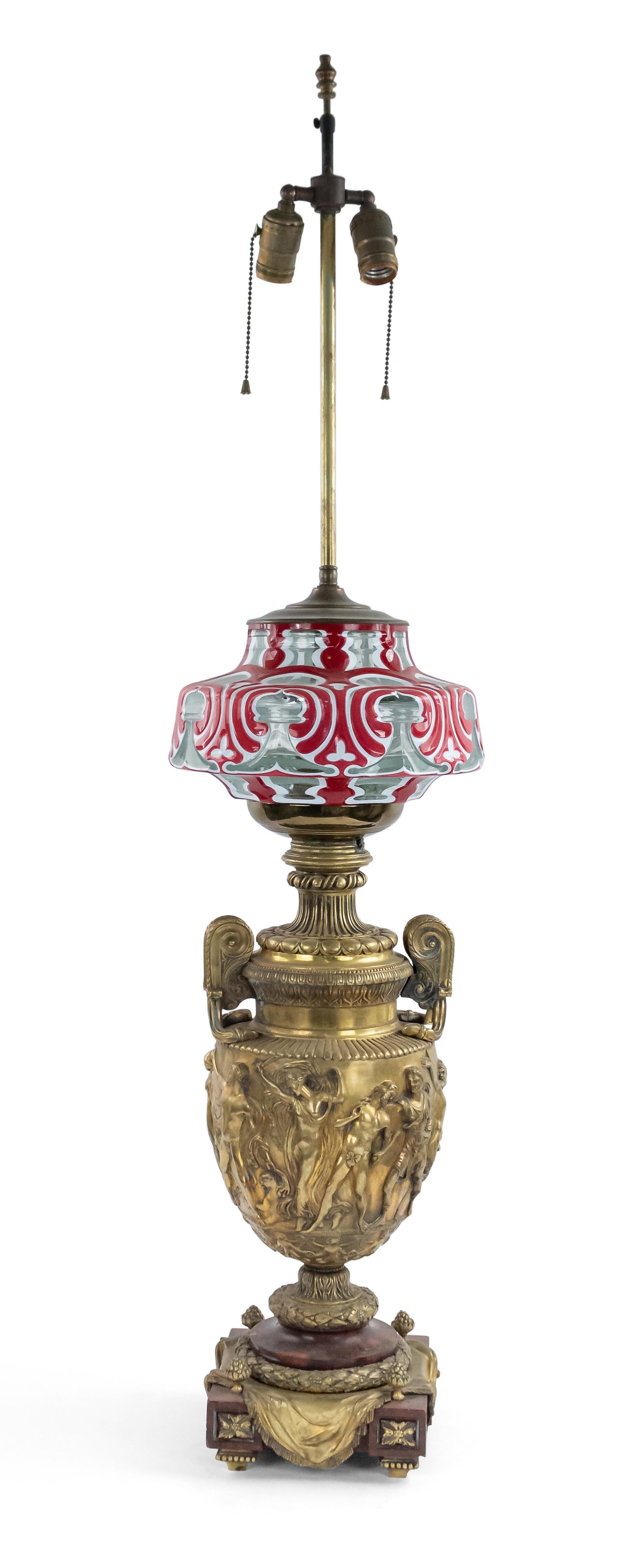 Pair of French Victorian bronze urn shaped table lamps with classical figures in relief below a white and red glass overlay font on a square red marble base (1 fount as is).
  