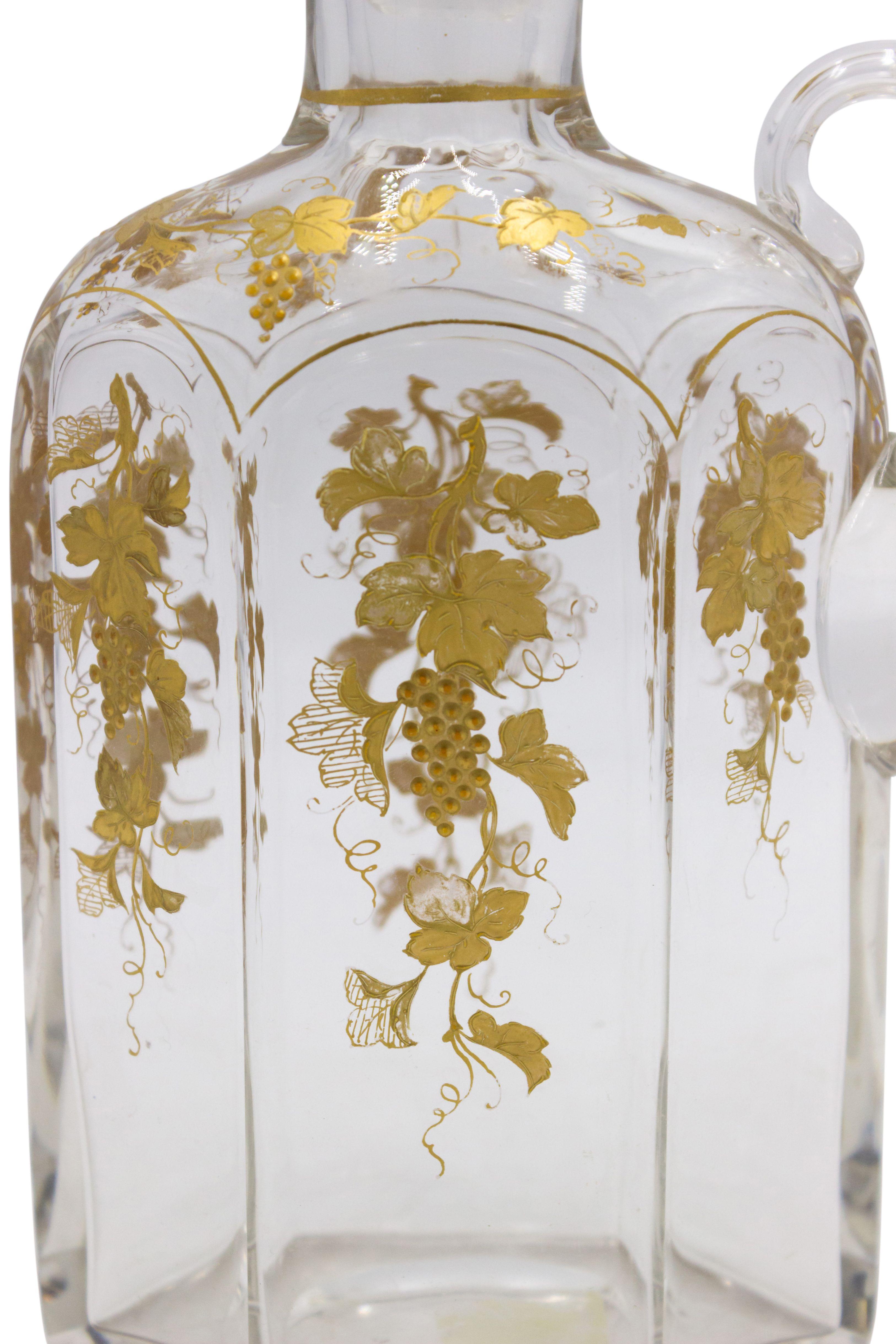 French Victorian crystal decanter with gold floral decoration and a small handle.