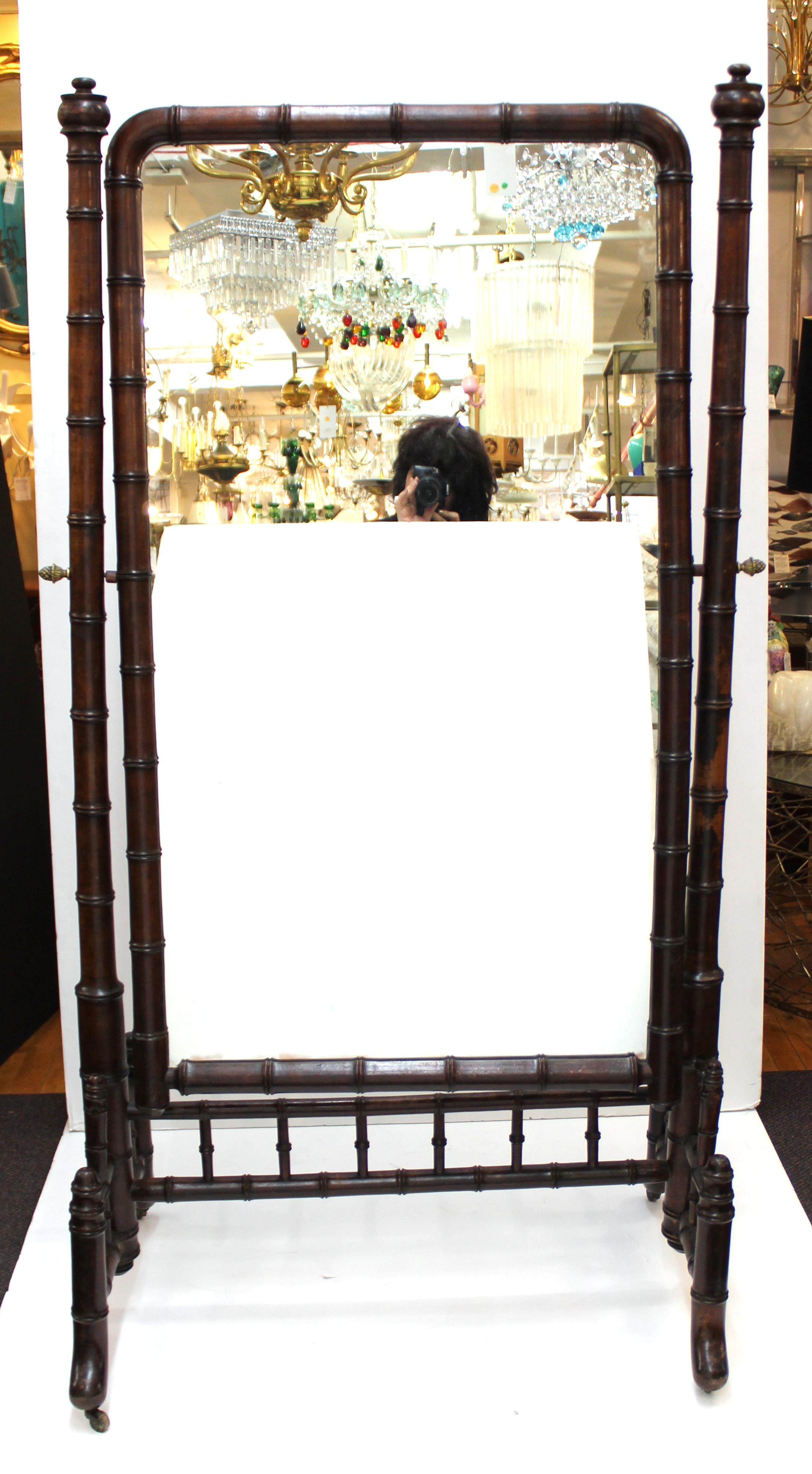 French 19th century Victorian faux bamboo cheval mirror in mahogany. The piece has pineapple finials holding up the mirror panel and moves on brass casters. Made in the circa 1880s in France. In great vintage condition with age-appropriate wear.