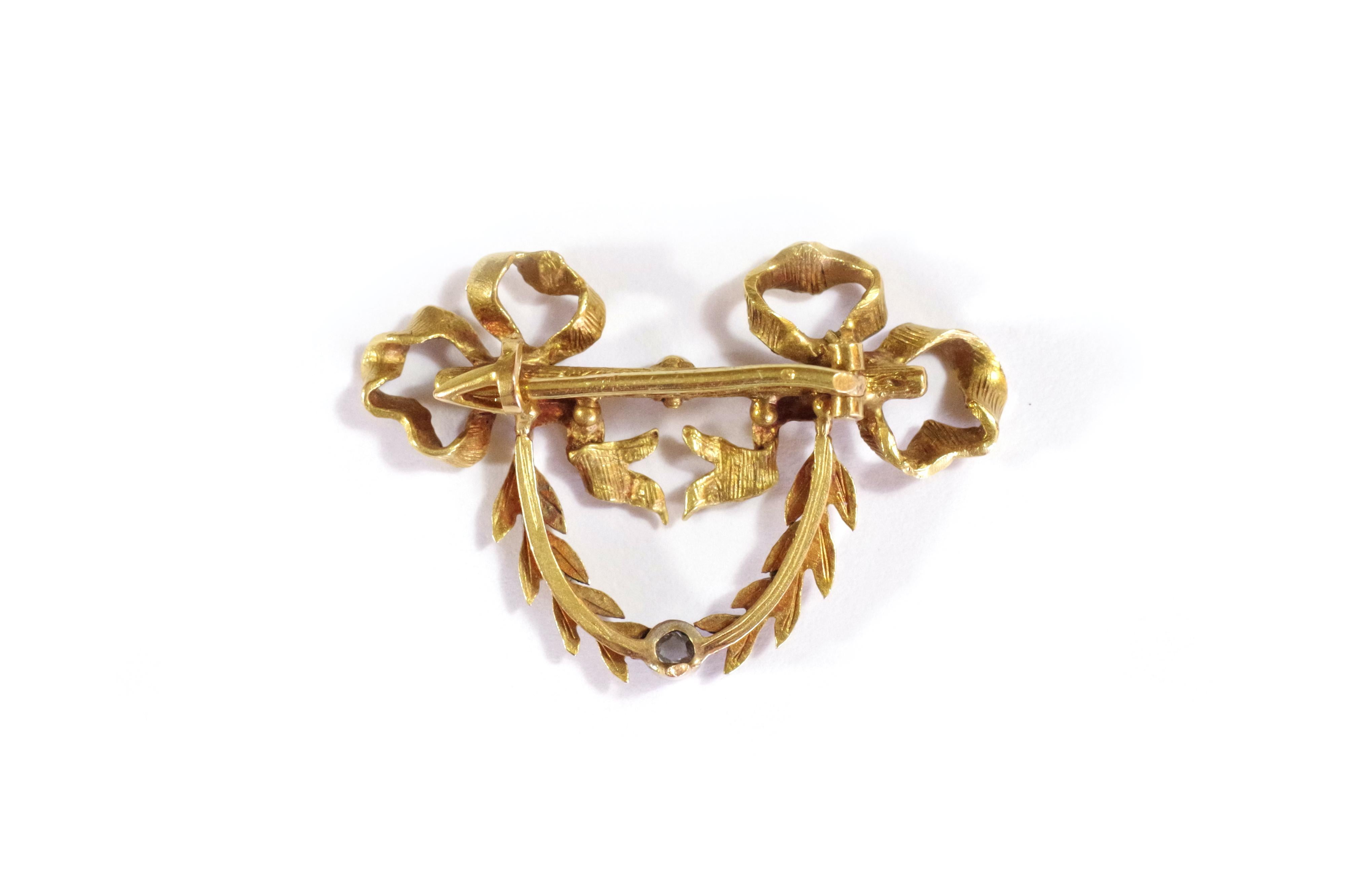 French Victorian garland brooch in gold 18 karat. Brooch decorated with ribbon bows and branches hanging on a straight branch. In the center of this one, a pearl. Below the brooch, in a white gold pearl setting, a rose-cut diamond. Antique brooch