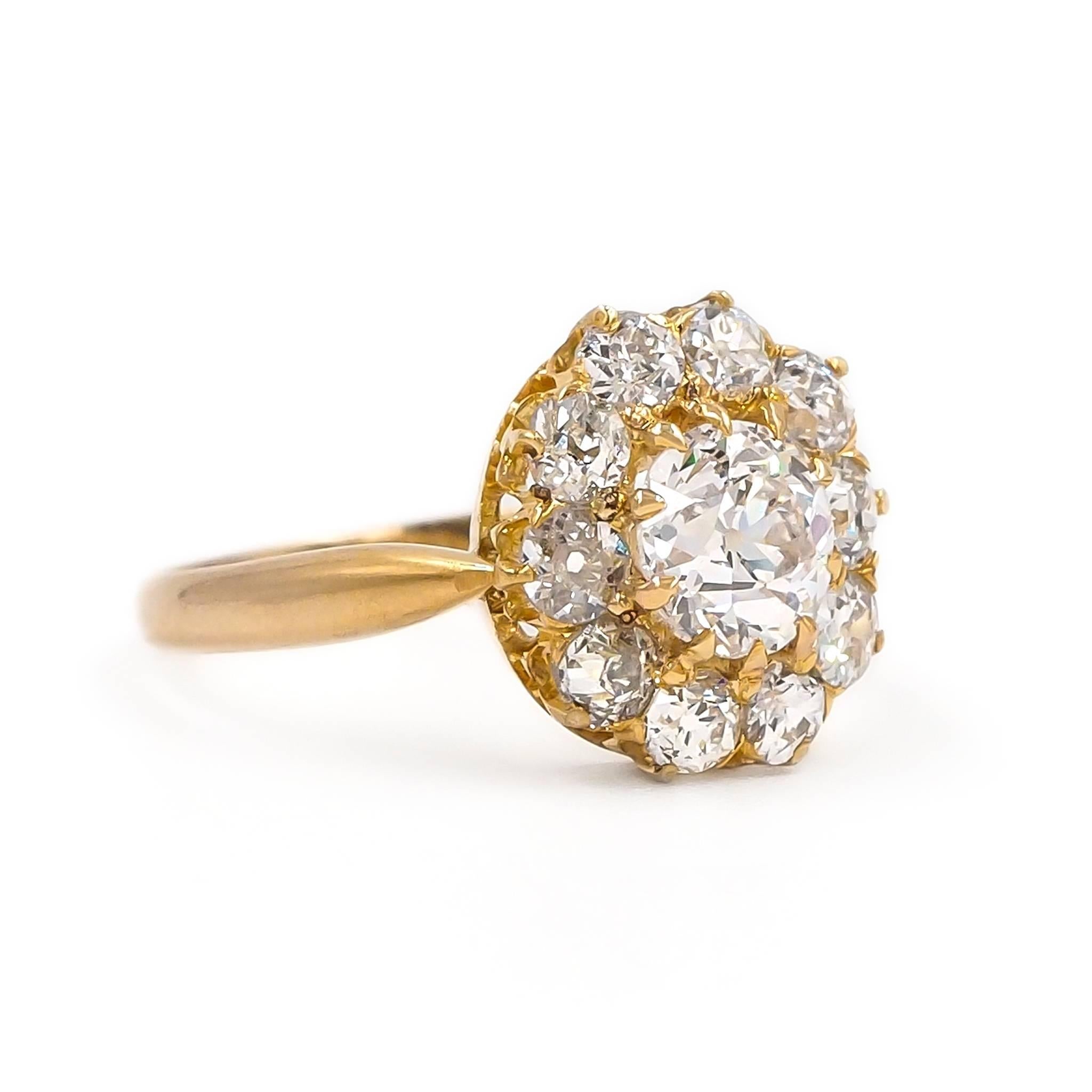 A classic Cluster Ring of French Origin composed of 18 Karat Yellow Gold. This Victorian era ring (circa 1890) features a center stone 1.26 Carat Old European Cut Diamond. Surrounded by 10 Old Mine Cut Diamonds weighing 1.20 Cts in total.  A