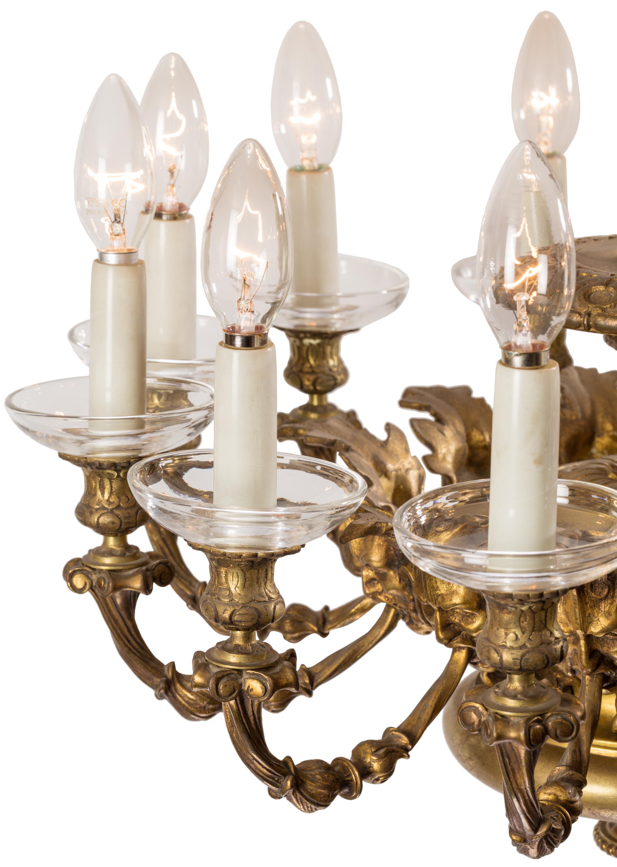 This French gilt brass 12-light chandelier seems to take its overall structure from the gas chandeliers (gasoliers) of the 1850s and 1860s, but having no gas cocks or external wiring, this lamp was made for electricity, probably in the late 19th or