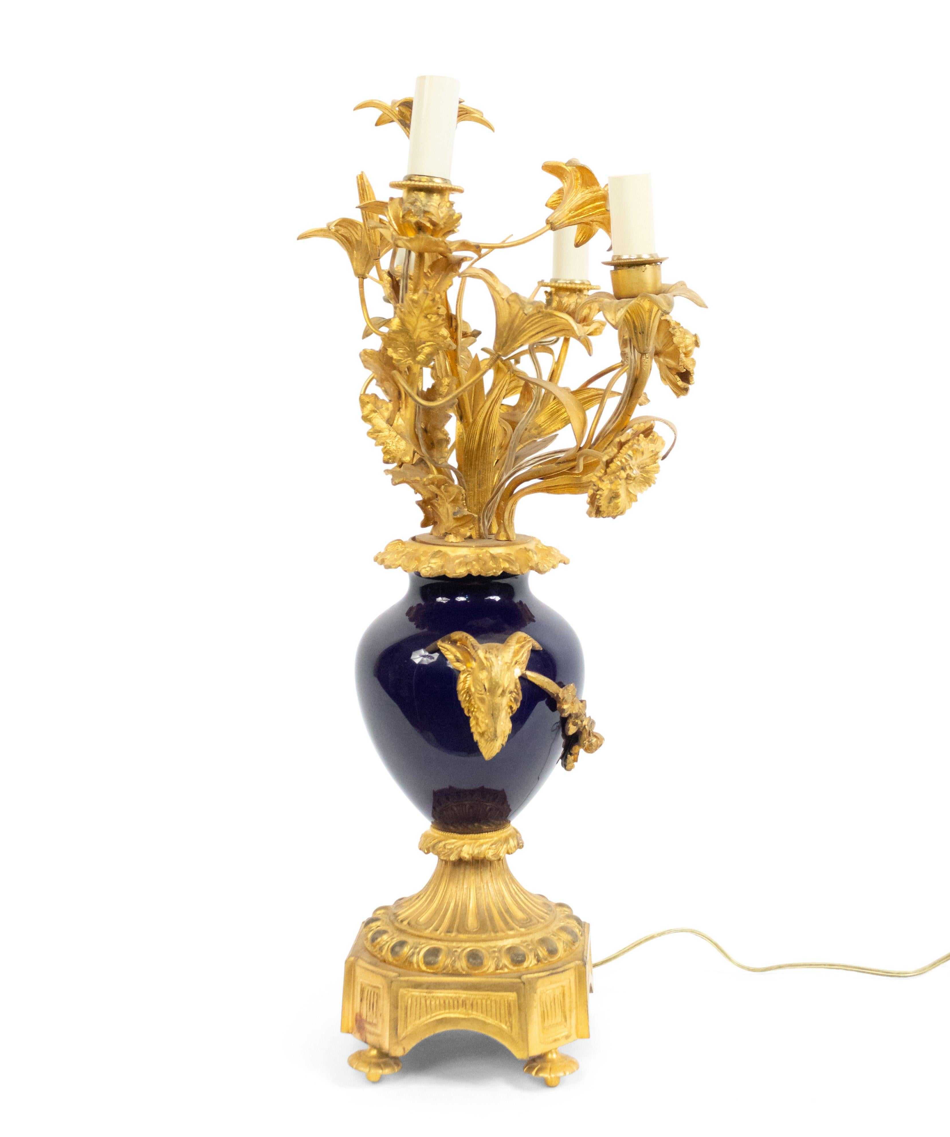 French Victorian (19th-20th Century) gilt bronze four-light candelabra (wired as a lamp) with floral arms over a porcelain blue urn with rams head handles culminating in a footed bronze base.