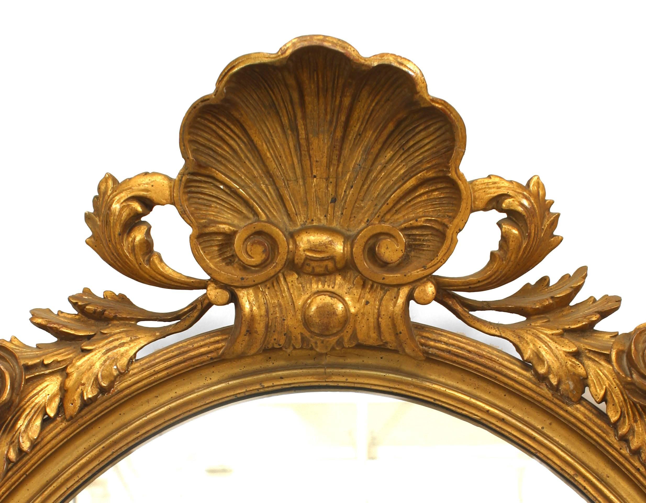 French Victorian oval giltwood wall mirror with a carved shell pediment surrounded by carved floral trim.
