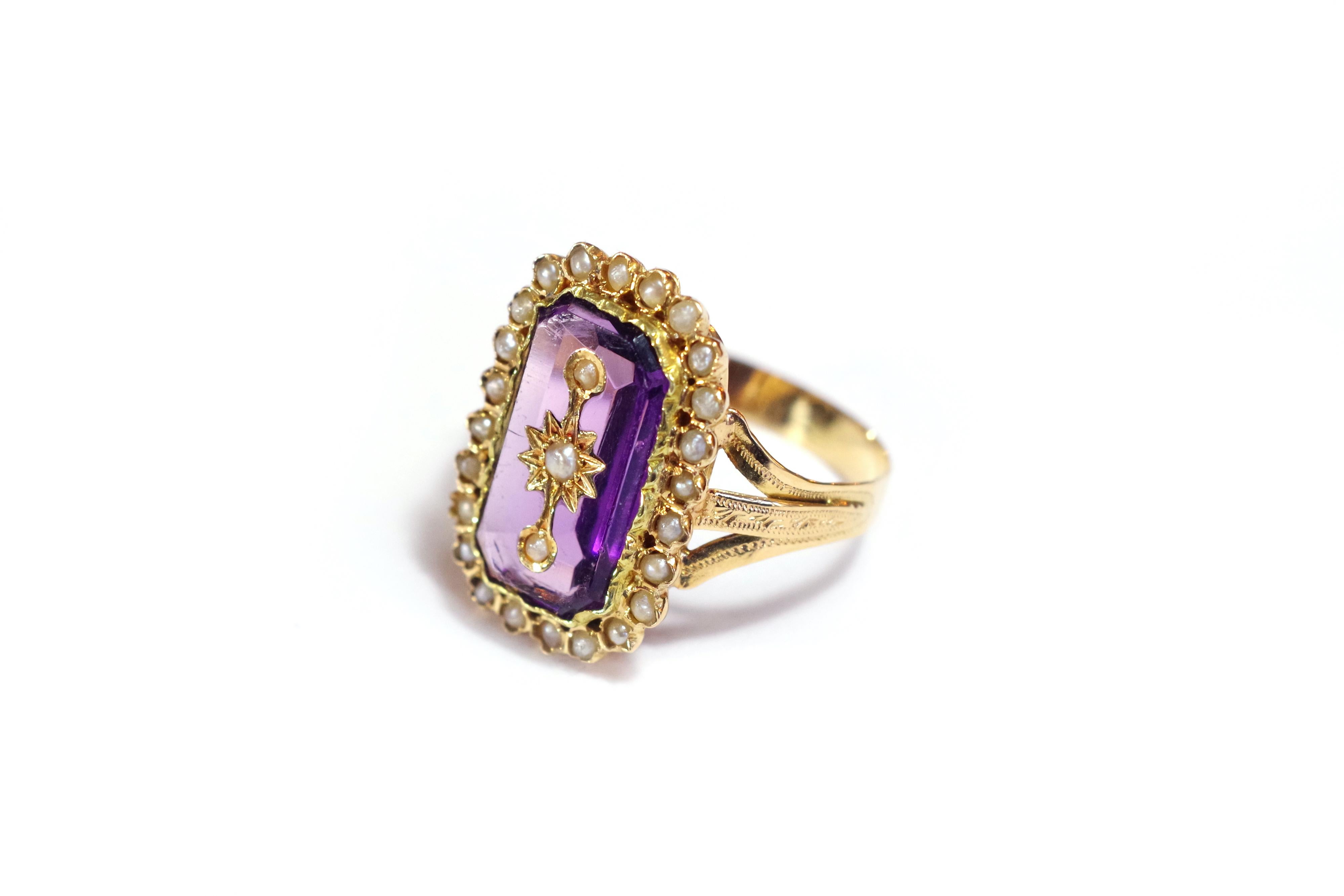 French Victorian pearl gold ring in yellow 18 karat gold. The ring is with a faceted purple glass imitating amethyst, on which are encrusted three seed pearls in a golden and starry decoration. The glass is surrounded by 23 half pearls. The ring is