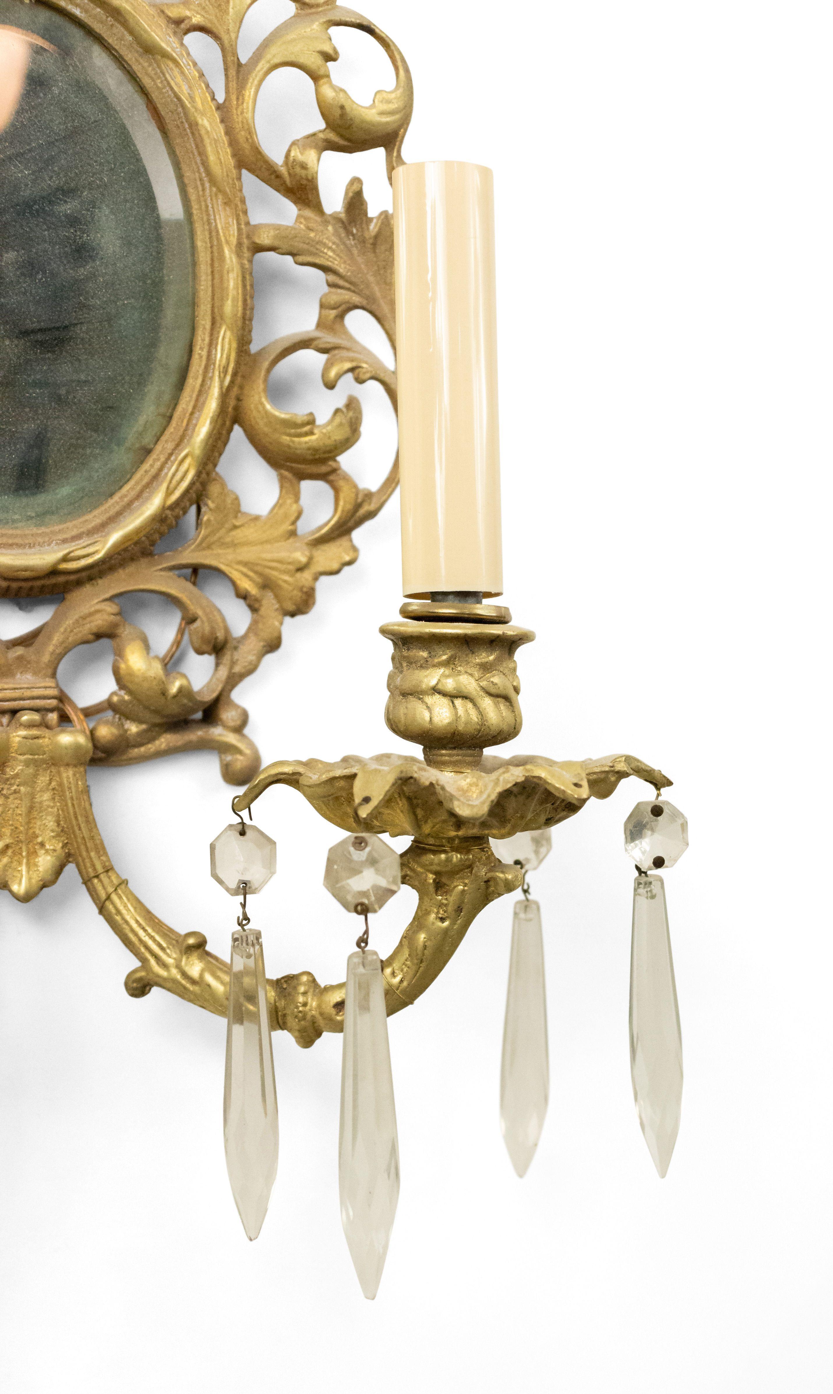French Victorian 20th century 2 light sconce in gilt bronze with scrolling foliate arms emanating from a filigree oval back with a beveled mirror insert (marked Glo-Mar Artworks, NY).