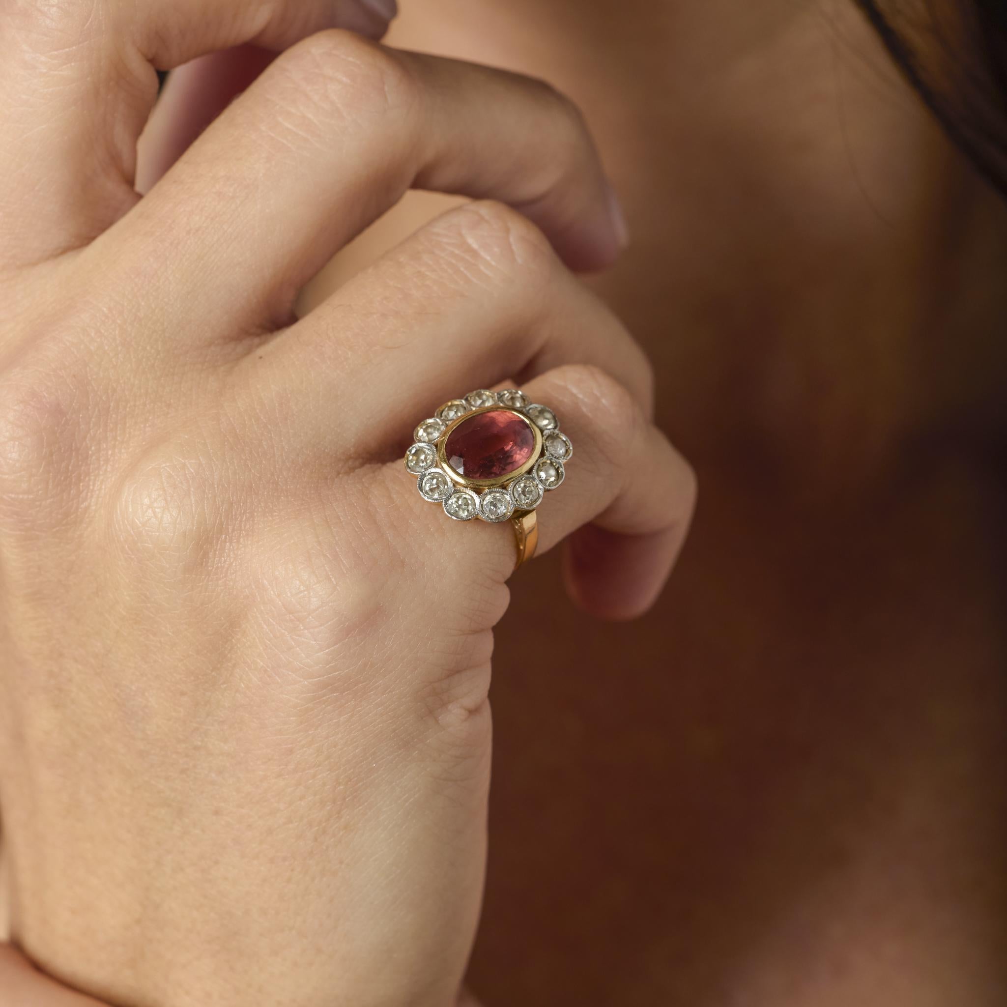 Romantic and refined, this French Victorian cluster ring embodies the opulence and artistry of turn-of-the-century design. At its center glows a richly hued 2.55 carat tourmaline, its vibrant tone enhanced by a halo of twelve old mine cut diamonds