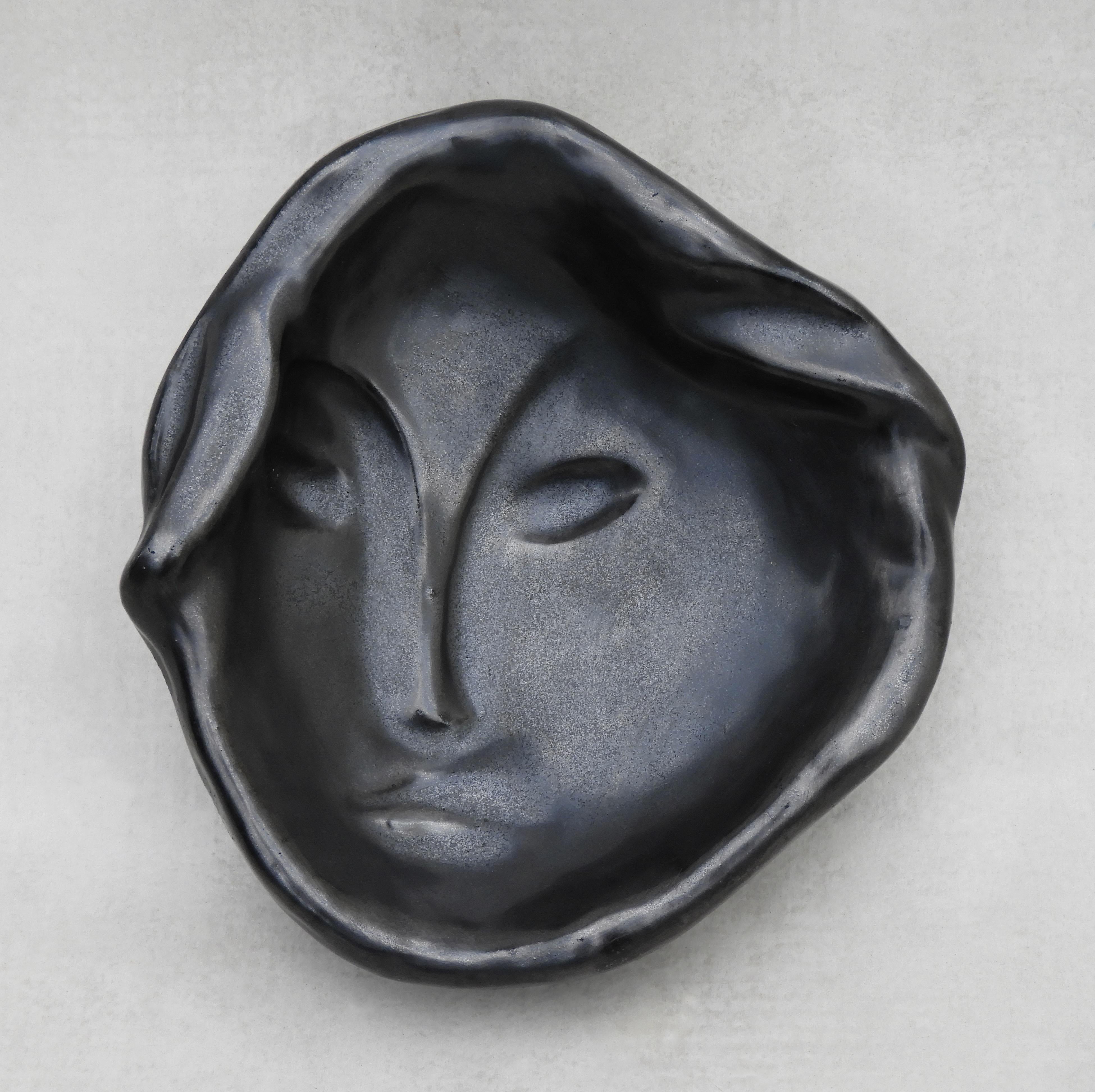Elegant Vide Poche from French ceramic studio Ricard, 1950s France.

Beautifully handcrafted catch-all dish, depicting the face of a young woman in concave bas-relief and finished in satin black glaze.

Stylishly simple, a gorgeous example of