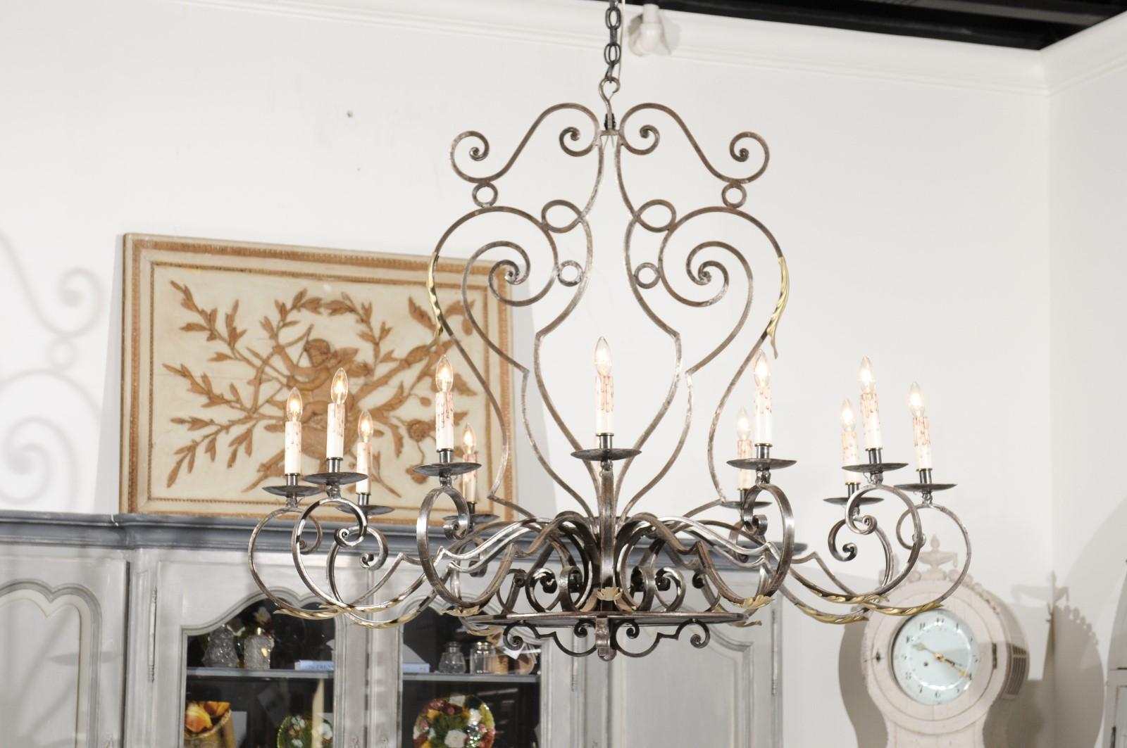 SOLD A French 12-light wrought-iron chandelier from the 20th century, with scrolling accents and acanthus leaves. Created in France during the 20th century, this vintage chandelier features a beautifully scrolling wrought-iron armature discreetly