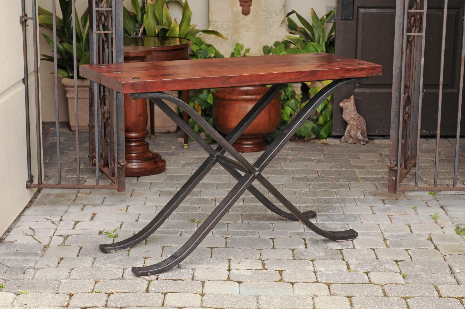 A vintage French narrow walnut and iron table from the mid-20th century, with curving x-form base. Born in France during the mid-century period, this stylish table features a rectangular planked walnut top accented with large nailheads, sitting