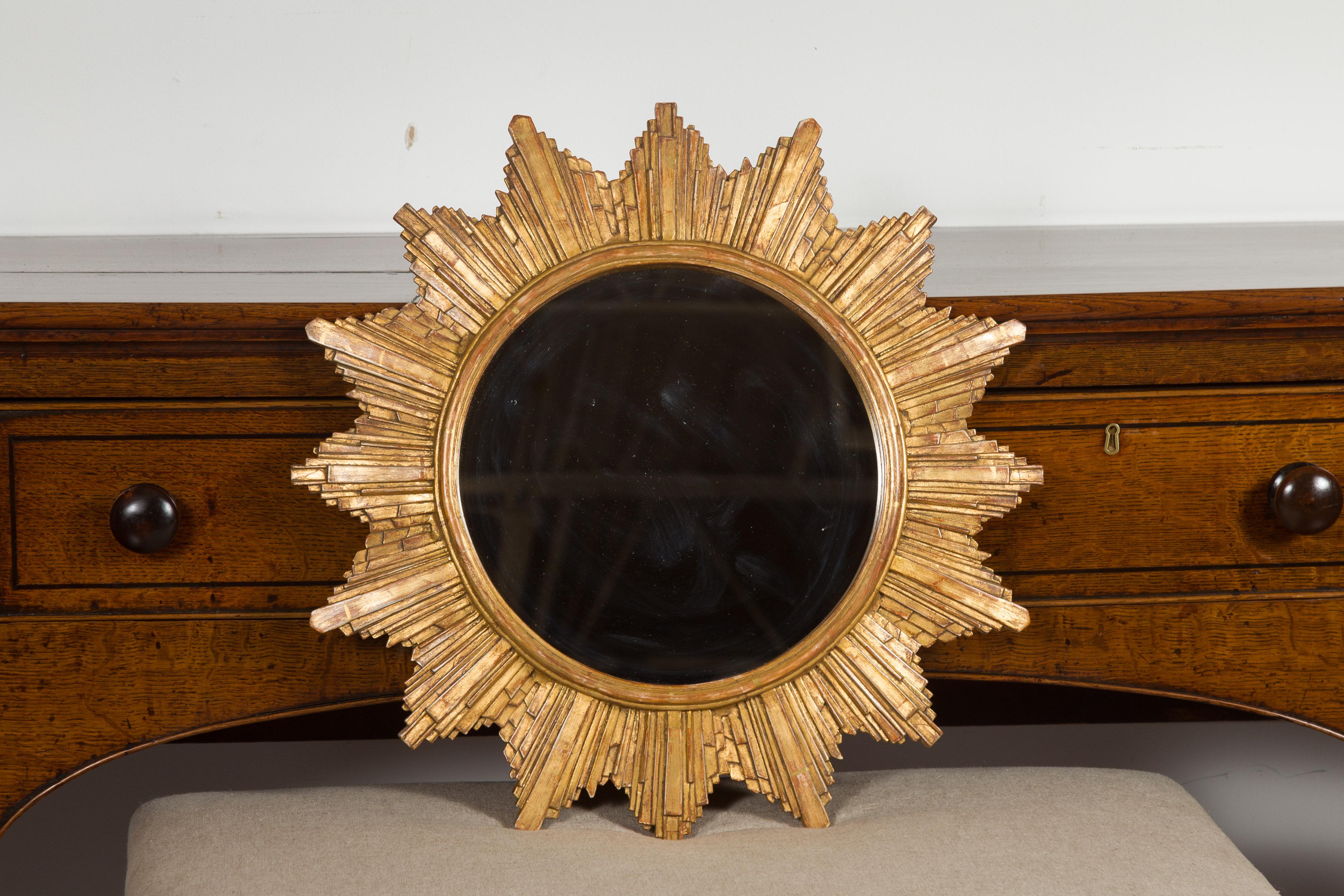 A French vintage gilt composition sunburst from the late 20th century, with rays of varying sizes and flat mirror. Born in France during the 1970s, this sunburst features a clear mirror plate surrounded by a molded inner frame, from which are