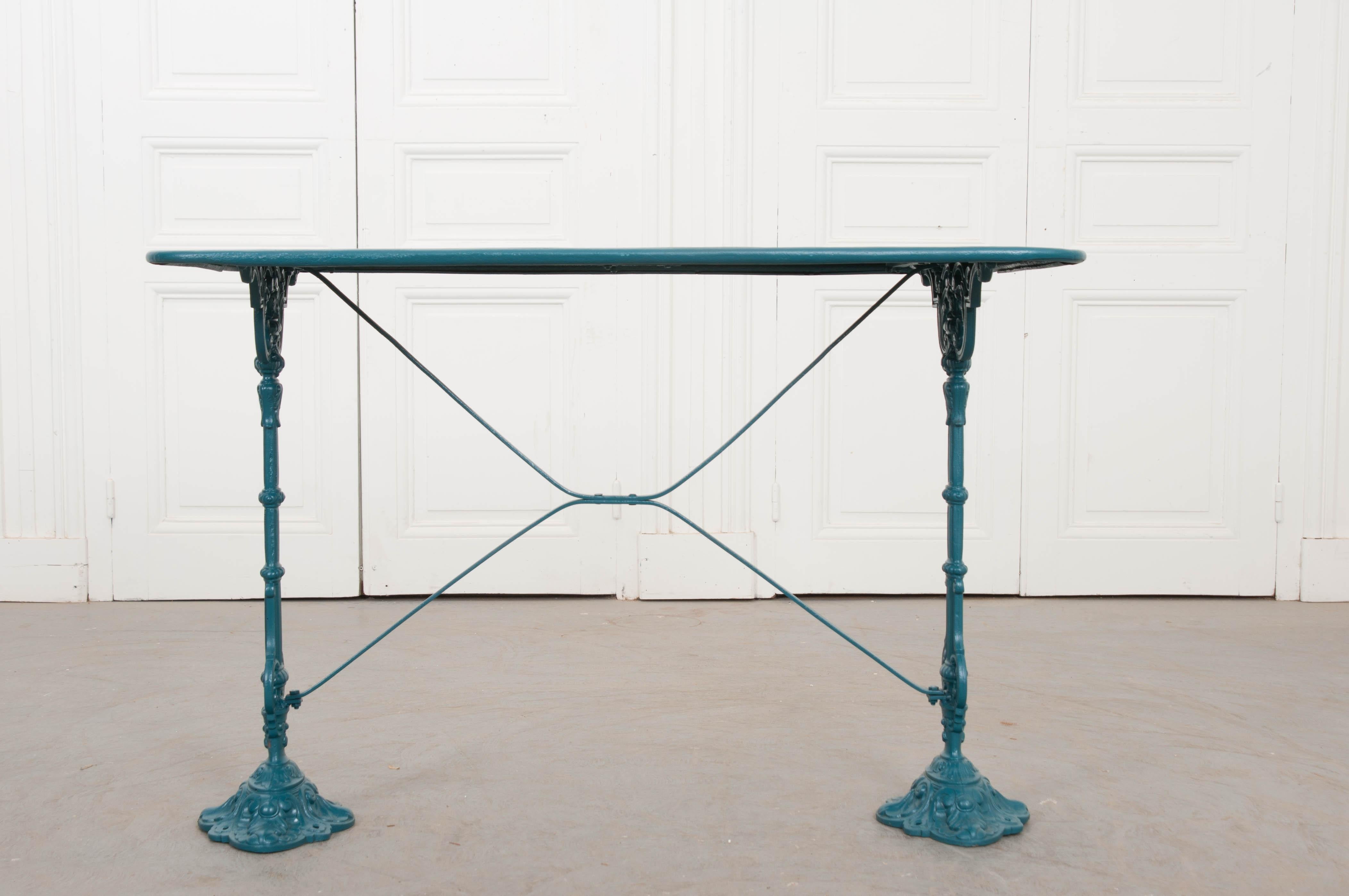 A charming vintage painted cast-iron and sheet metal bistro table, circa 1910, from France. The rectangular sheet-metal surface rests on two notched cast-iron legs stabilized by an X-form stretcher above stylized diamond-shaped feet. It has recently