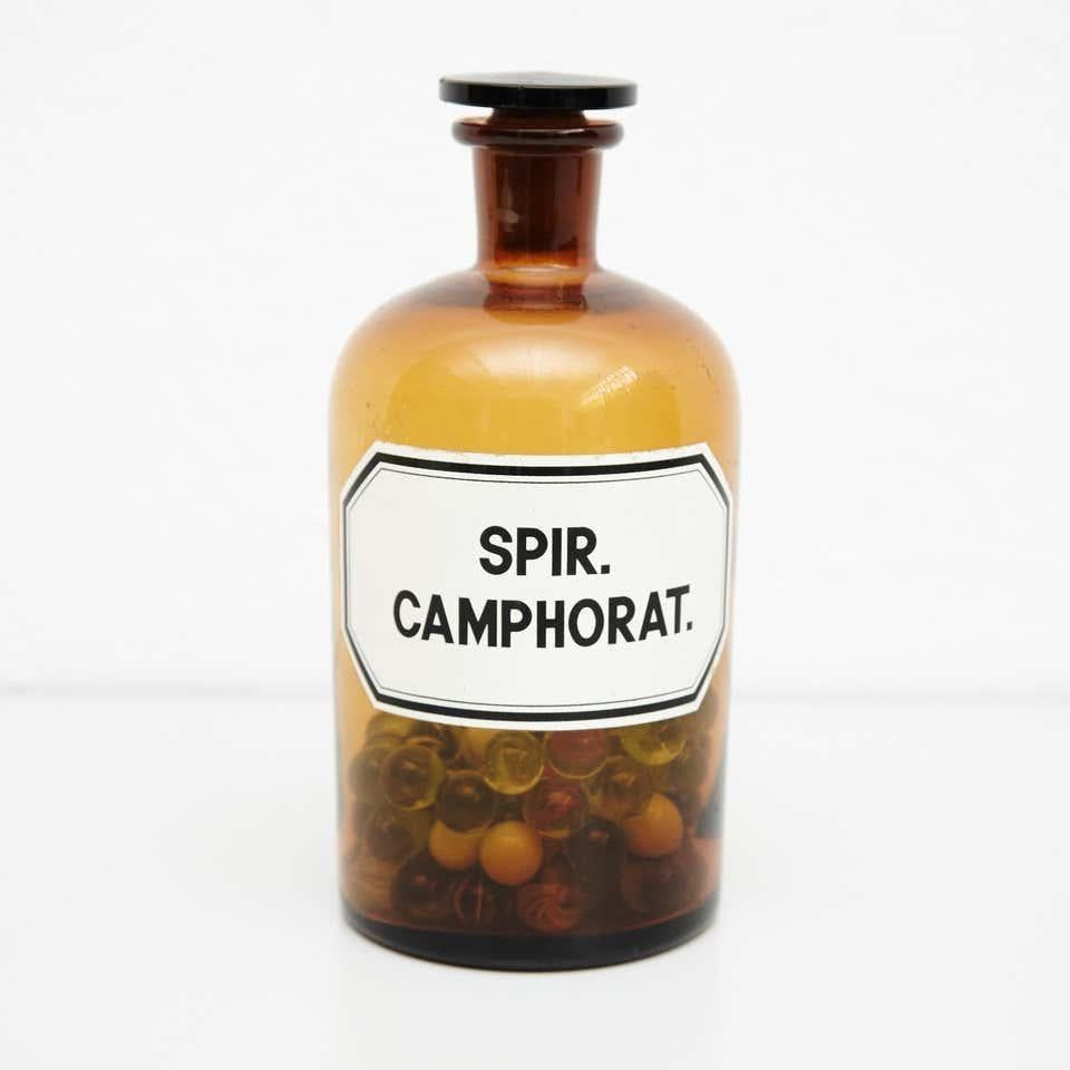 French vintage Amber glass pharmacy bottle.  By unknown manufacturer, France, circa 1930.    In original condition, with minor wear consistent with age and use, preserving a beautiful patina.    Materials:  Amber glass    Dimensions:  ø 10.5 cm x H