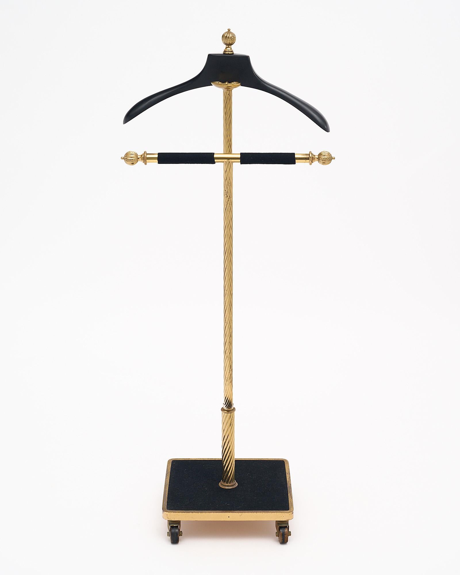 Valet from the Art Deco period in France; of brass featuring a “torsado” design and a gilded brass handcuff holder The hanger is made of ebonized wood and the base is covered in a black felt. It sits on four original working casters. A handsome
