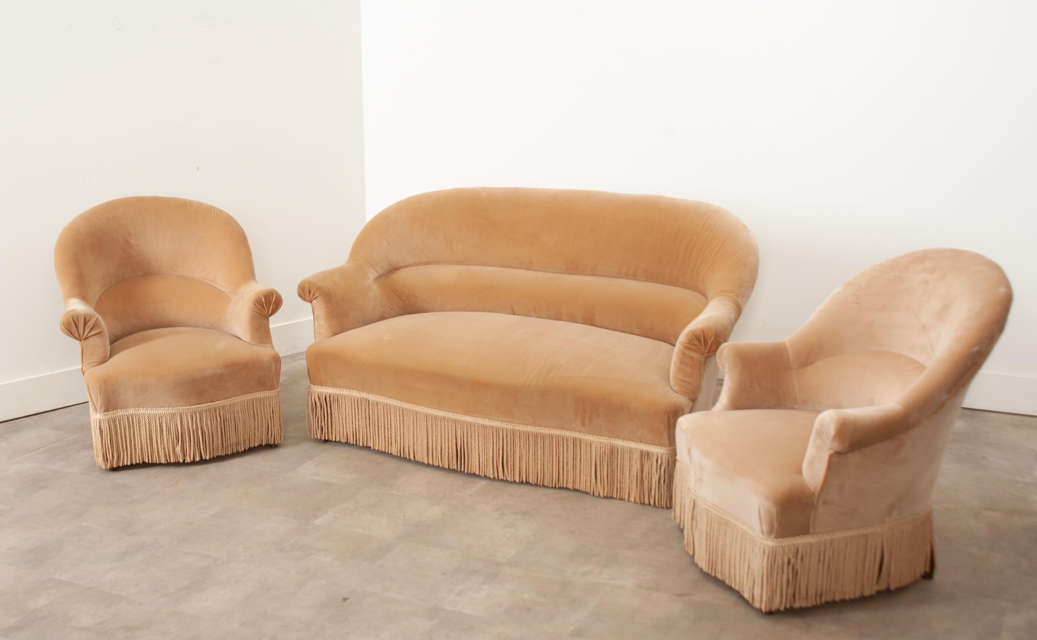 An eye-catching and very comfortable French vintage Art Deco style parlor set with settee and two chairs. Sand colored velvet covers the entire set featuring classic shapes and plush fringe. A wonderful combination of comfort and composition, this