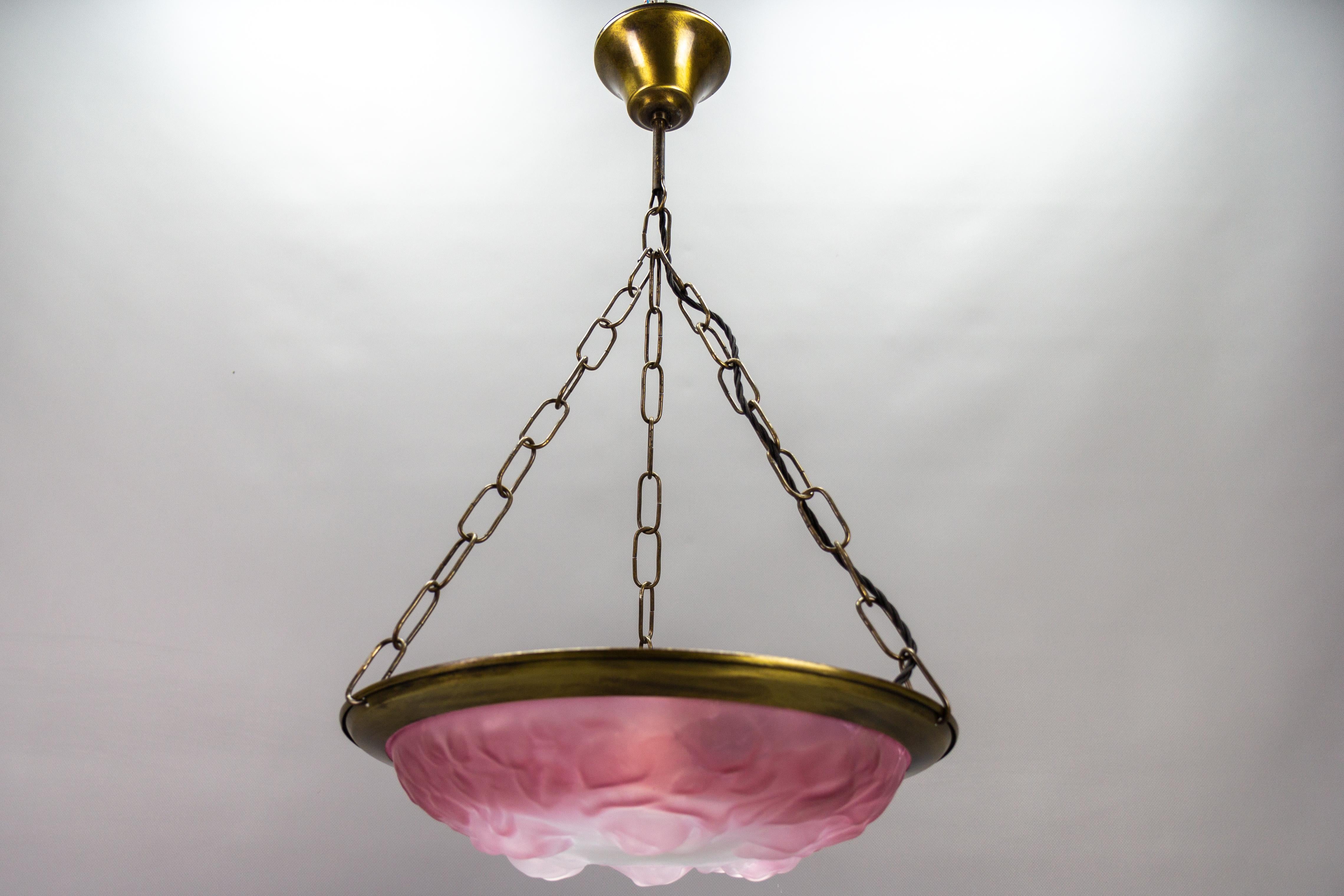 French vintage Art Deco style pink and white glass pendant light with roses, circa the 1980s.
This beautiful vintage pendant lamp features a frosted molded glass lampshade in pink and white colors with floral patterns of roses held by metal and
