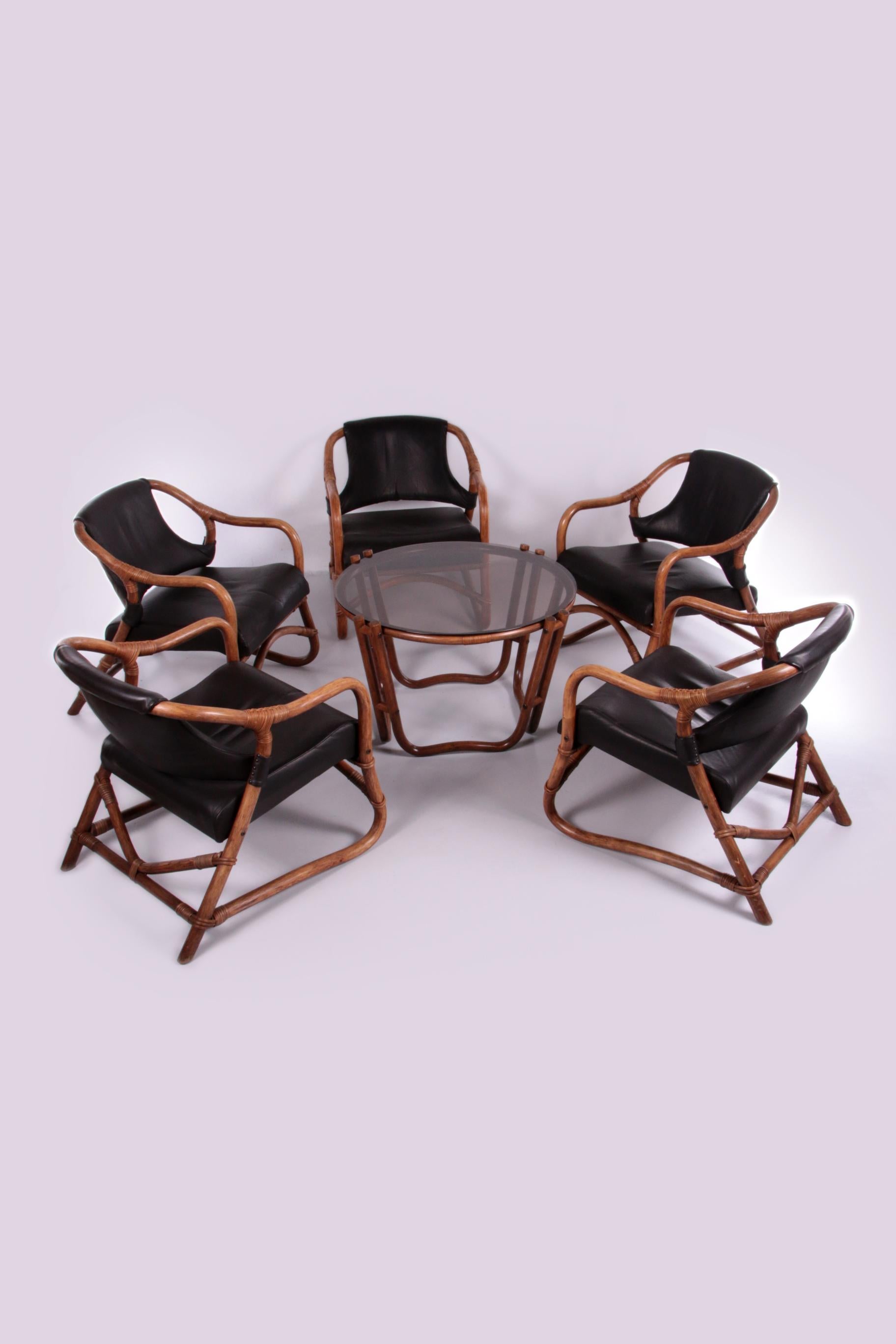 A beautiful and stylish bamboo lounge set consisting of five chairs and a matching table.

The bamboo produced in the frame of the chairs and the table has a beautiful deep brown patina. The table has a table top made of dark glass and the chairs