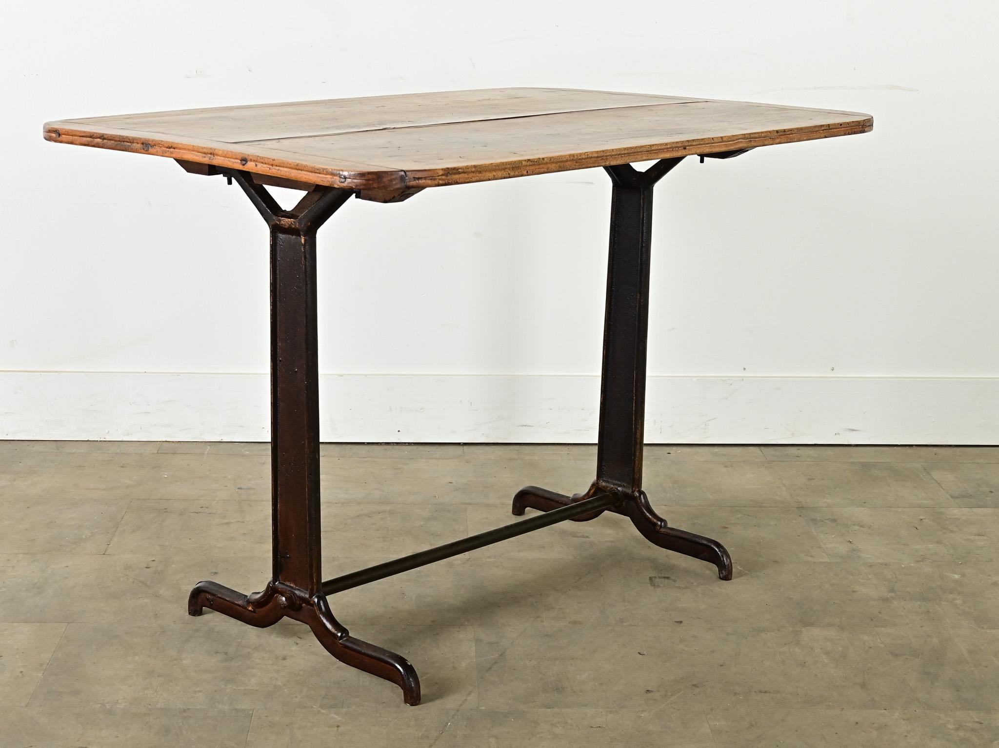 Table de bistrot française vintage avec plateau en peuplier massif et base en fonte. Les planches de bois sont maintenues ensemble par un assemblage à rainure et languette, le grain est patiné avec les cernes et les taches attendues, qui n'enlèvent