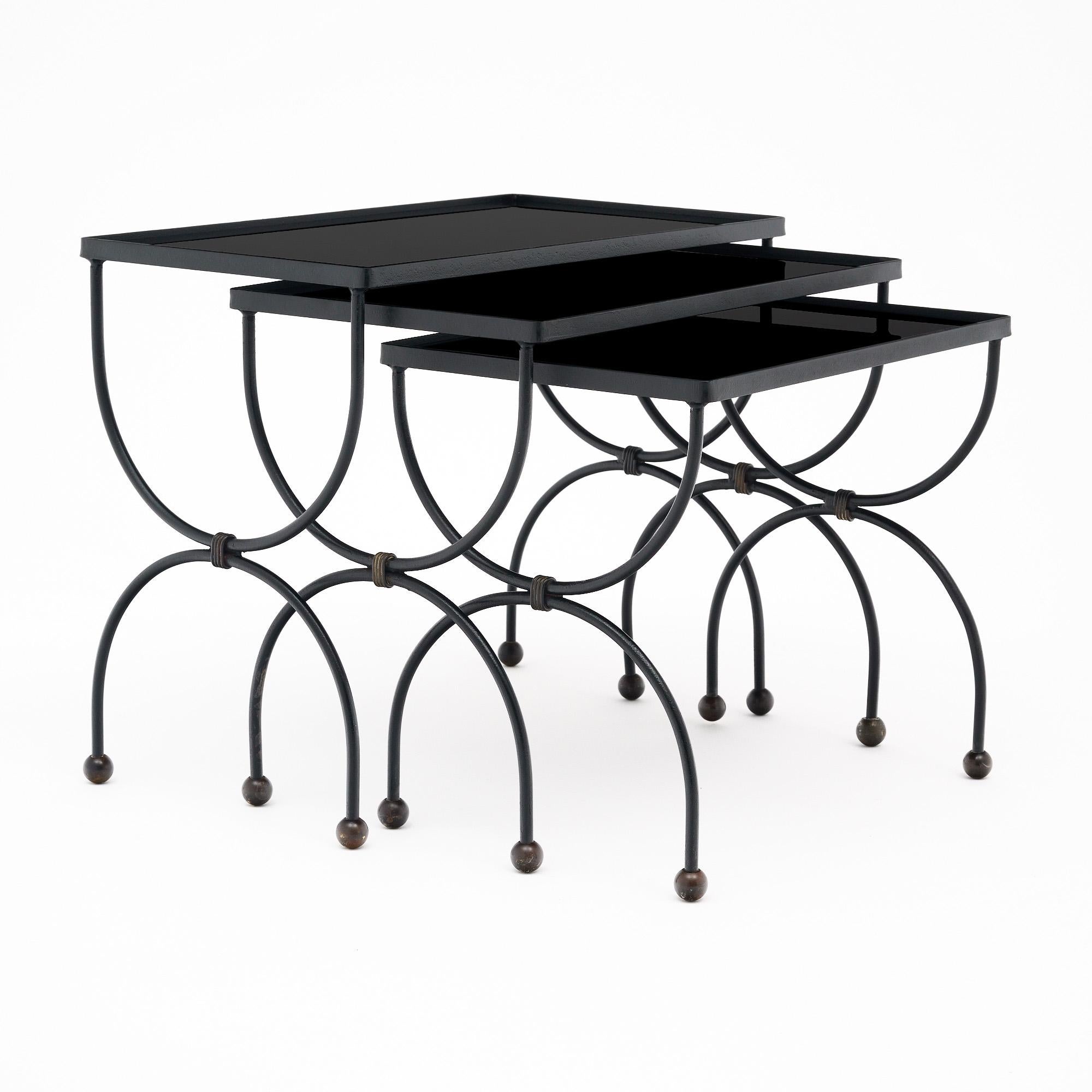 Satz von drei Nisttischen aus Frankreich im Art Déco-Stil. Diese Tische bestehen aus schwarzen Metallstrukturen mit curuleförmigen Beinen. Die Abdeckungen sind aus schwarzem Glas. Dieses Set ist in sehr schönem Vintage-Zustand - die Fotos geben den