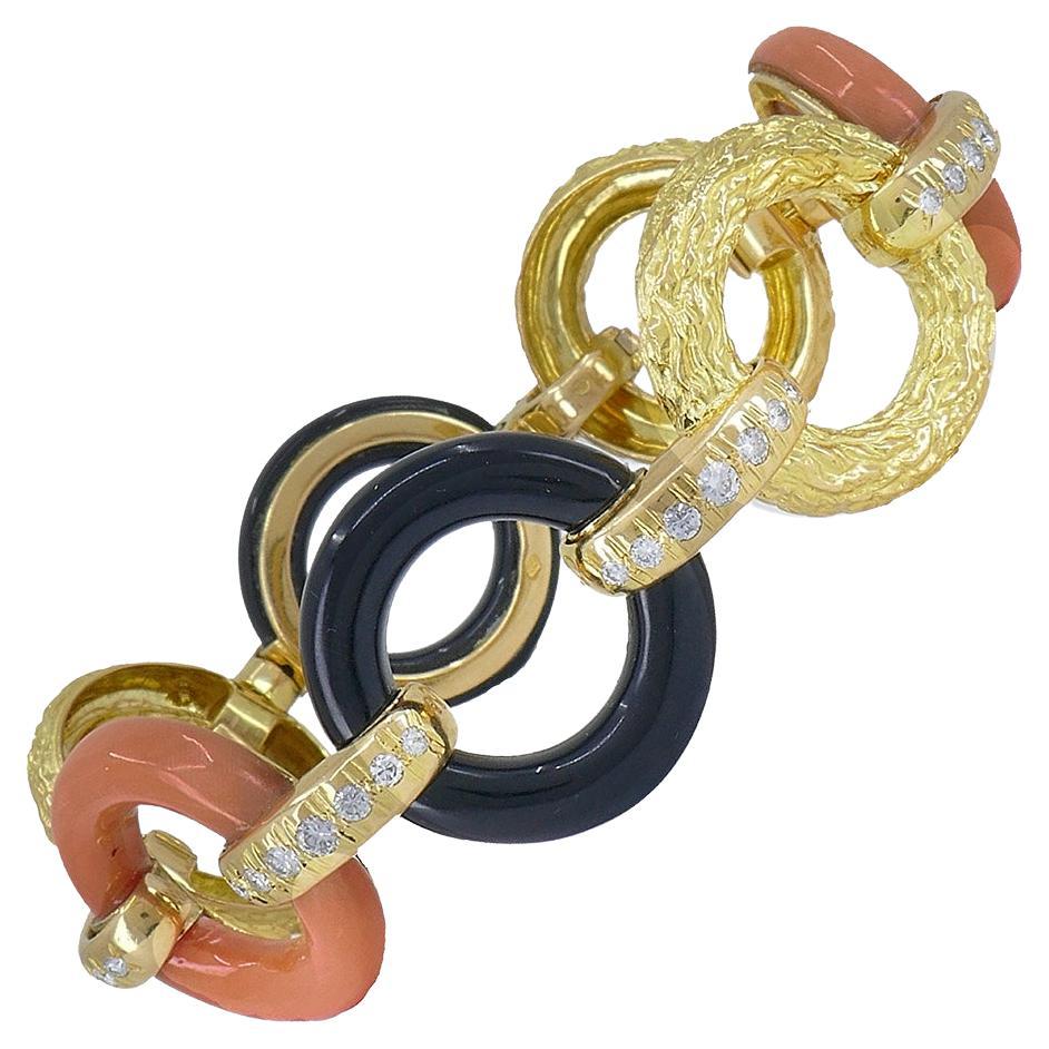 A beautiful vintage French bracelet, made of 18k yellow gold, featuring diamond, coral and black onyx.	
The vintage bracelet comprises seven round-shaped links connected by the horizontal loops. The loops are embellished with diamonds. The circles