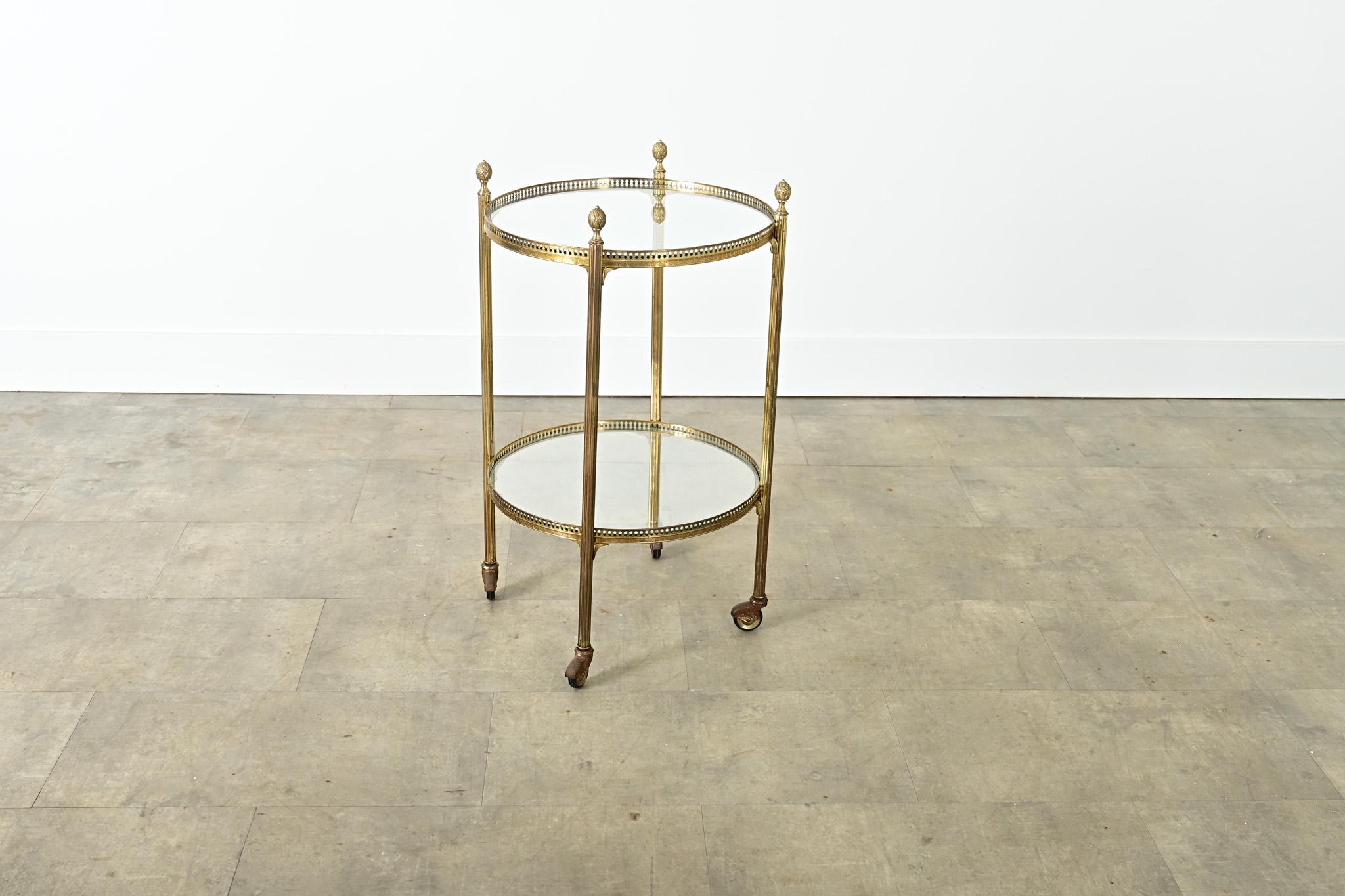 Una versátil mesa auxiliar redonda neoclásica francesa de latón y cristal de mediados de siglo, que se pondrá fácilmente a la altura de las circunstancias como carrito para servir en las fiestas. Cuatro patas de textura acanalada y remates de