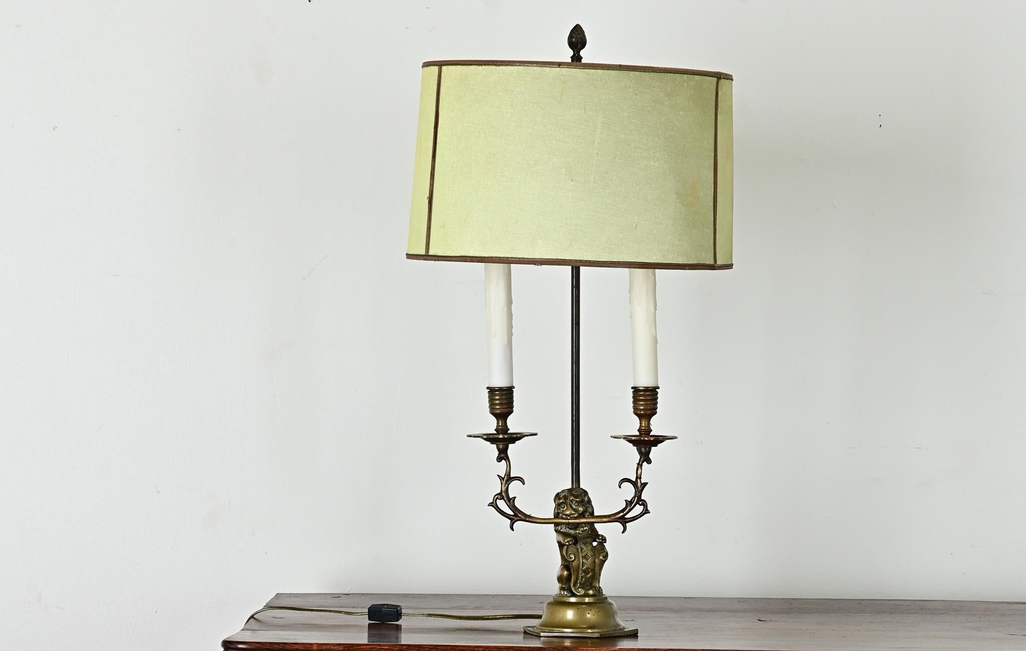 Incroyable lampe de table représentant un lion héraldique tenant dans ses dents deux bras de lampe en forme de vigne et tenant un bouclier à crête. L'abat-jour d'origine, en soie vert céladon, n'est pas dans le meilleur état mais est intéressant à