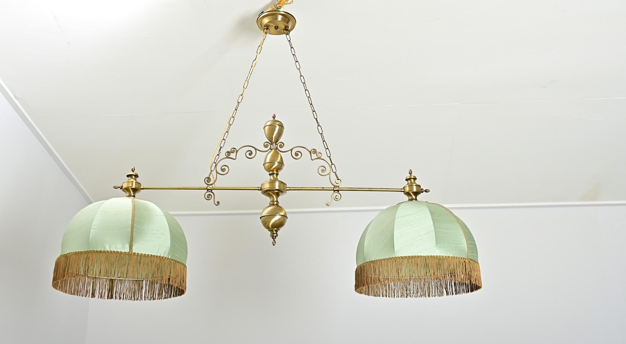 Fabulous vintage 20th century French billiard light fixture, composed of a long, horizontal stem supporting two domes of stretched silk in a gorgeous shade of celadon green. Fine scrollwork arches from the central counterbalance to the rod, a