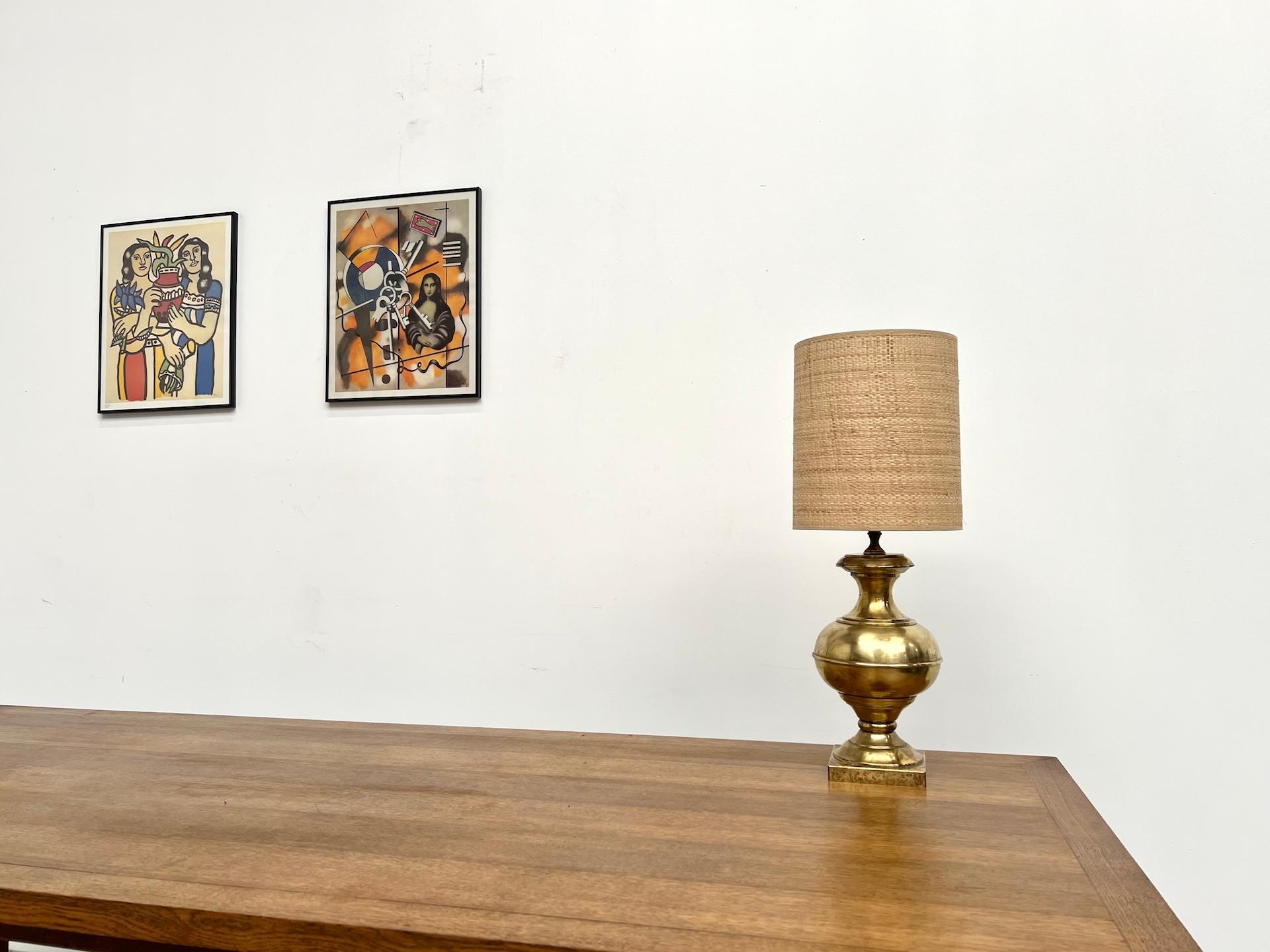 Maison Lecan presents this elegant vintage brass table lamp, crafted in the 1960s-70s.
Its curved base, with an amphora-like silhouette, rests on a square solid brass plinth.

The cylindrical lampshade in natural fiber adds a warm and organic touch,