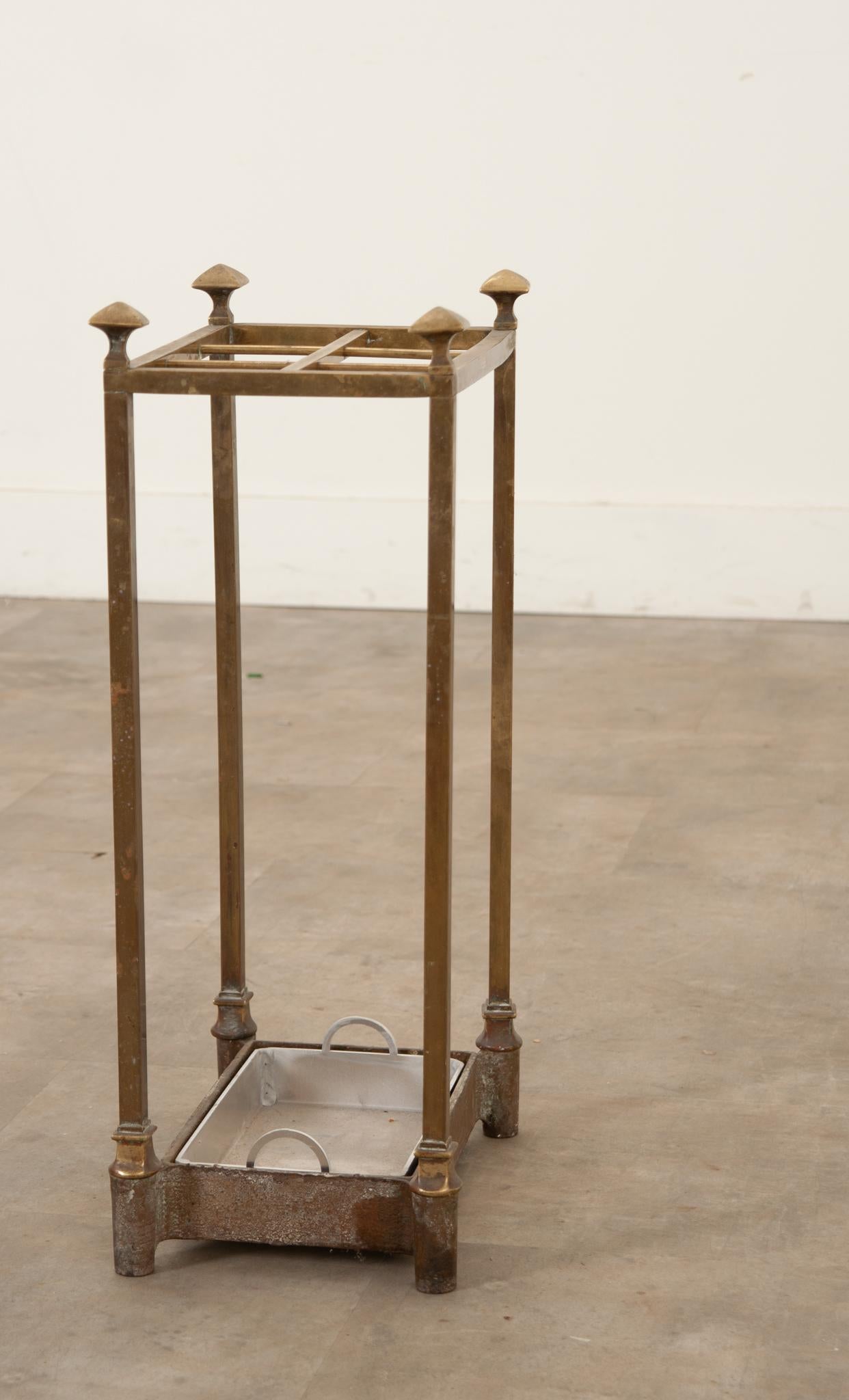 A vintage, brass segmented umbrella or walking stick stand made in France. This stand consists of 6 compartments for belongings and a new removable steel drip tray; its legs are topped with 4 decorative finials, and showcases a desirable aged