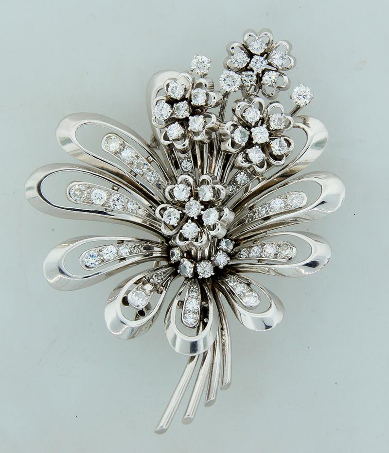 A classic vintage French brooch made of 18 karat gold and diamond.
It’s an open work, airy 18k white gold brooch designed as a bouquet of flowers. The larger flower is crafted of the open work gold petals with a line of diamonds staged in the