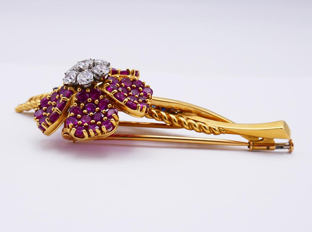 A stunning French brooch with ruby, sapphire and diamond that is a classic example of the 1960s floral design brooches. It’s a three-dimensional 18k gold Wild Rose brooch.

This colorful French flower pin is made of 18 karat yellow gold and set with
