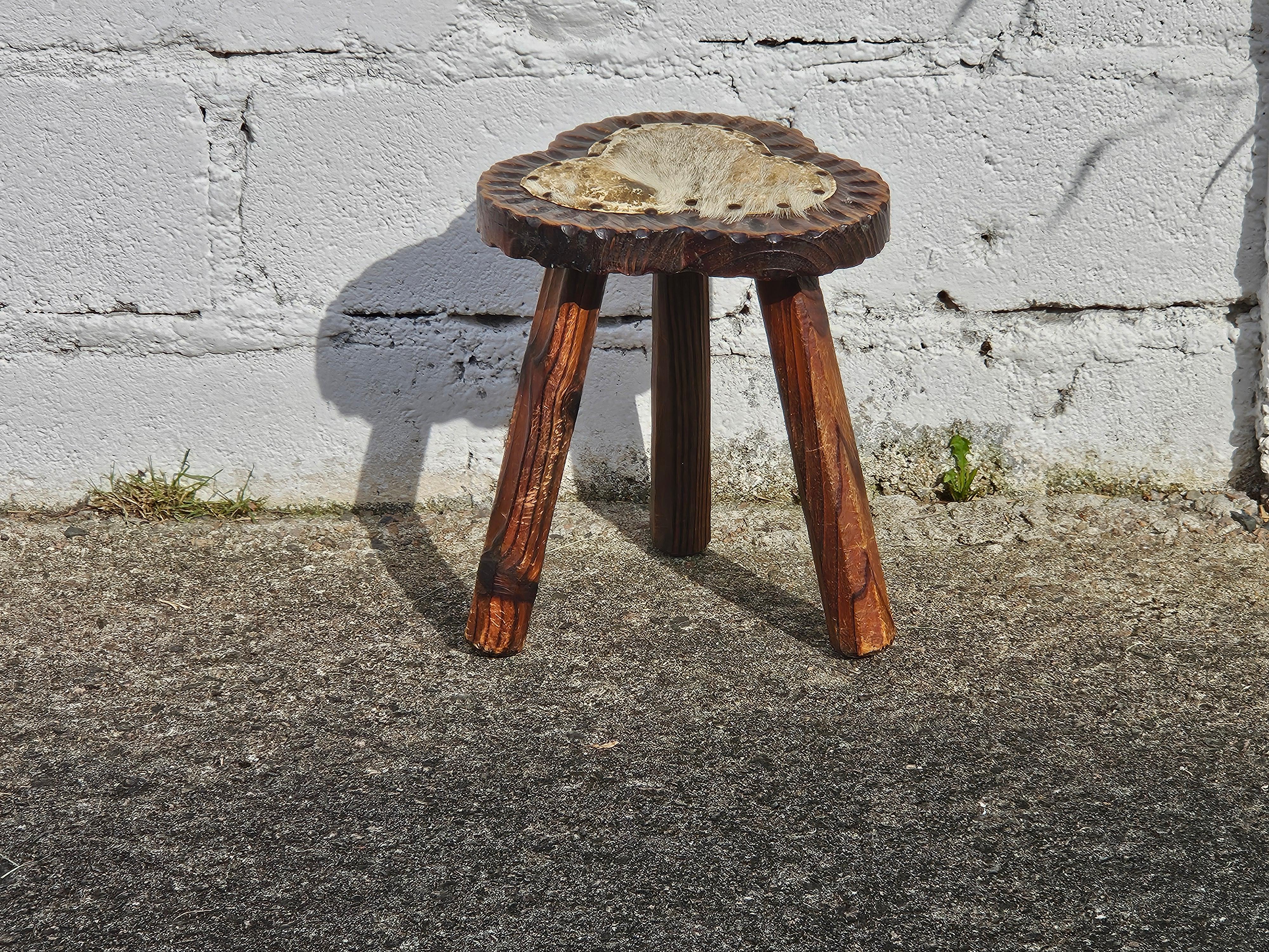 French Brutalist wooden Tripod Stool  from the 50s
Authentic Style - beautiful Wood - three-legged Stool with even nice Carvings on the Seat.
The seat is embellished by a small goat skin which is attached with upholstery nails.This underlines this