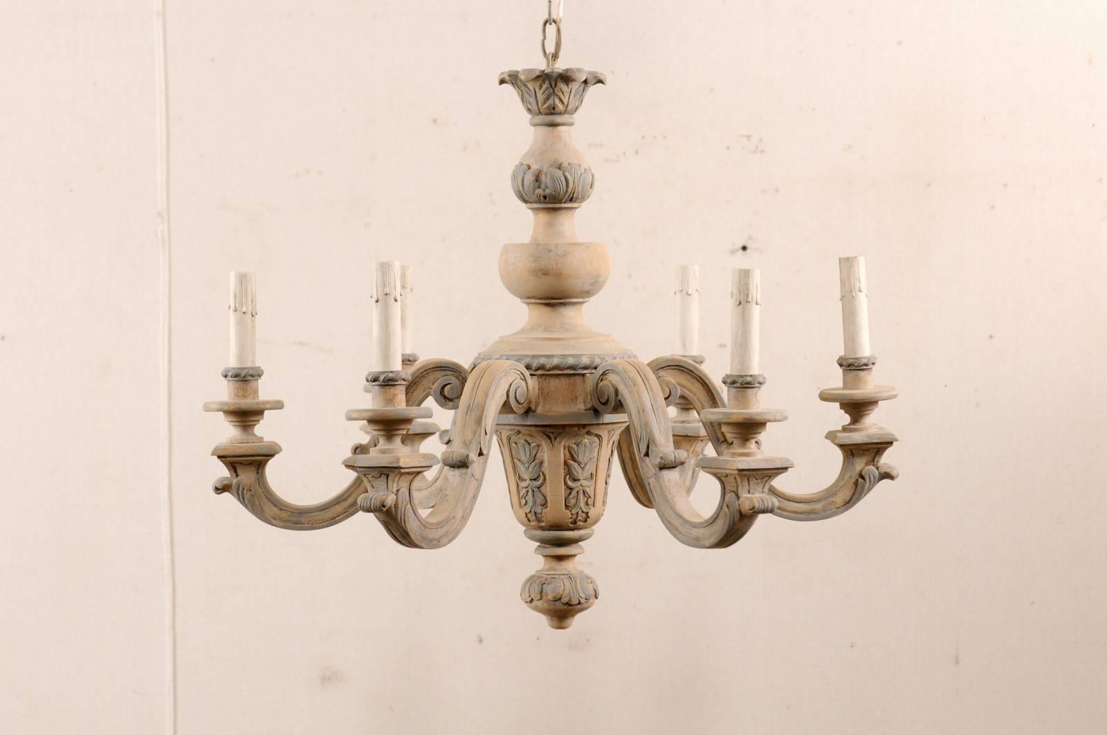 Un lustre vintage français en bois sculpté et peint à six lumières. Ce charmant lustre français du milieu du 20e siècle présente une colonne centrale sculptée avec six bras à volutes en forme de S émergeant vers l'extérieur:: chacun orné de motifs