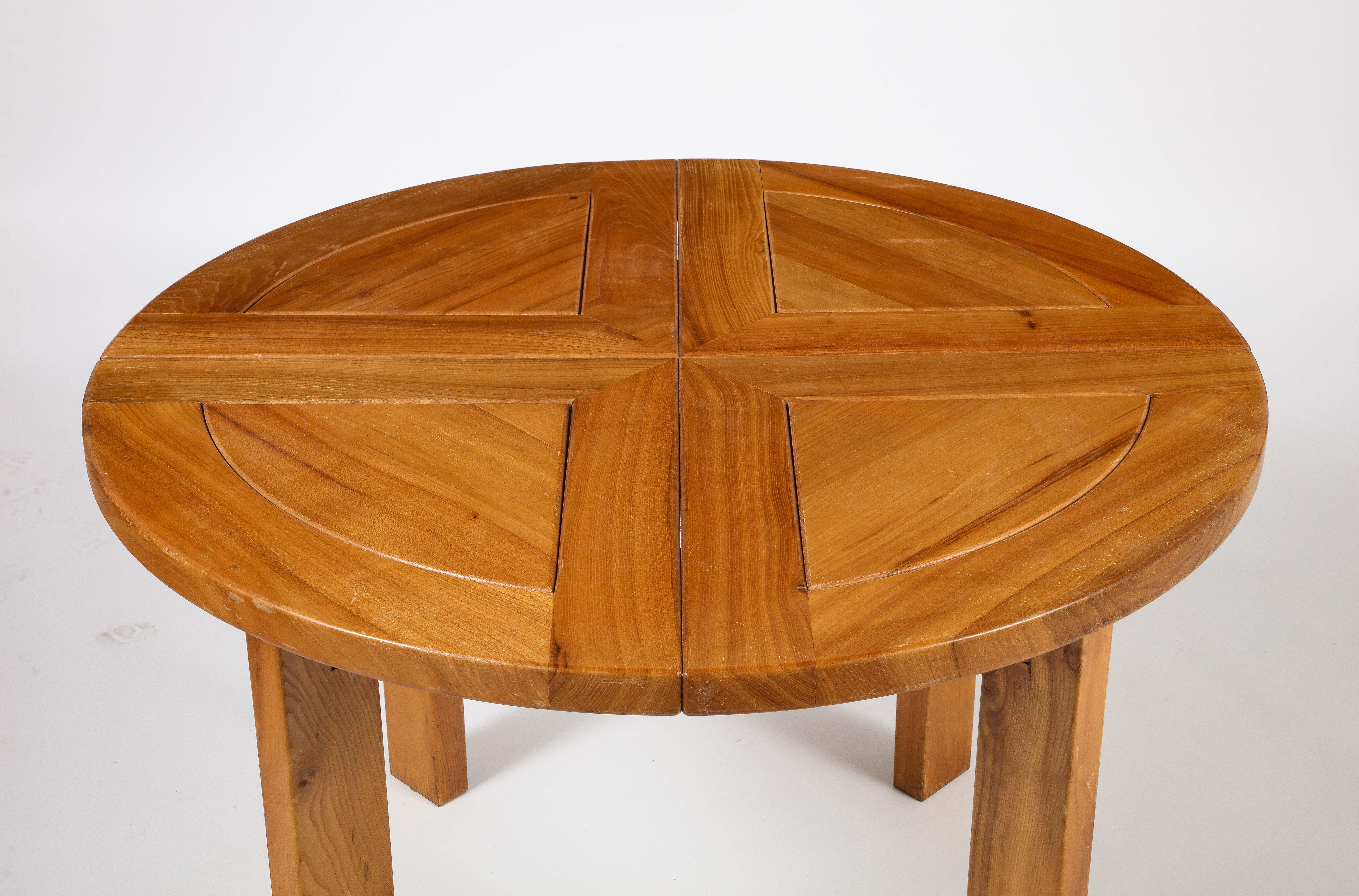 A stunning Maison Regain dining table executed in a rich and beautifully colored elm wood. The table is sturdy and combines a simplified yet complex design with solid construction details which characterize the works by Maison Regain. 
With