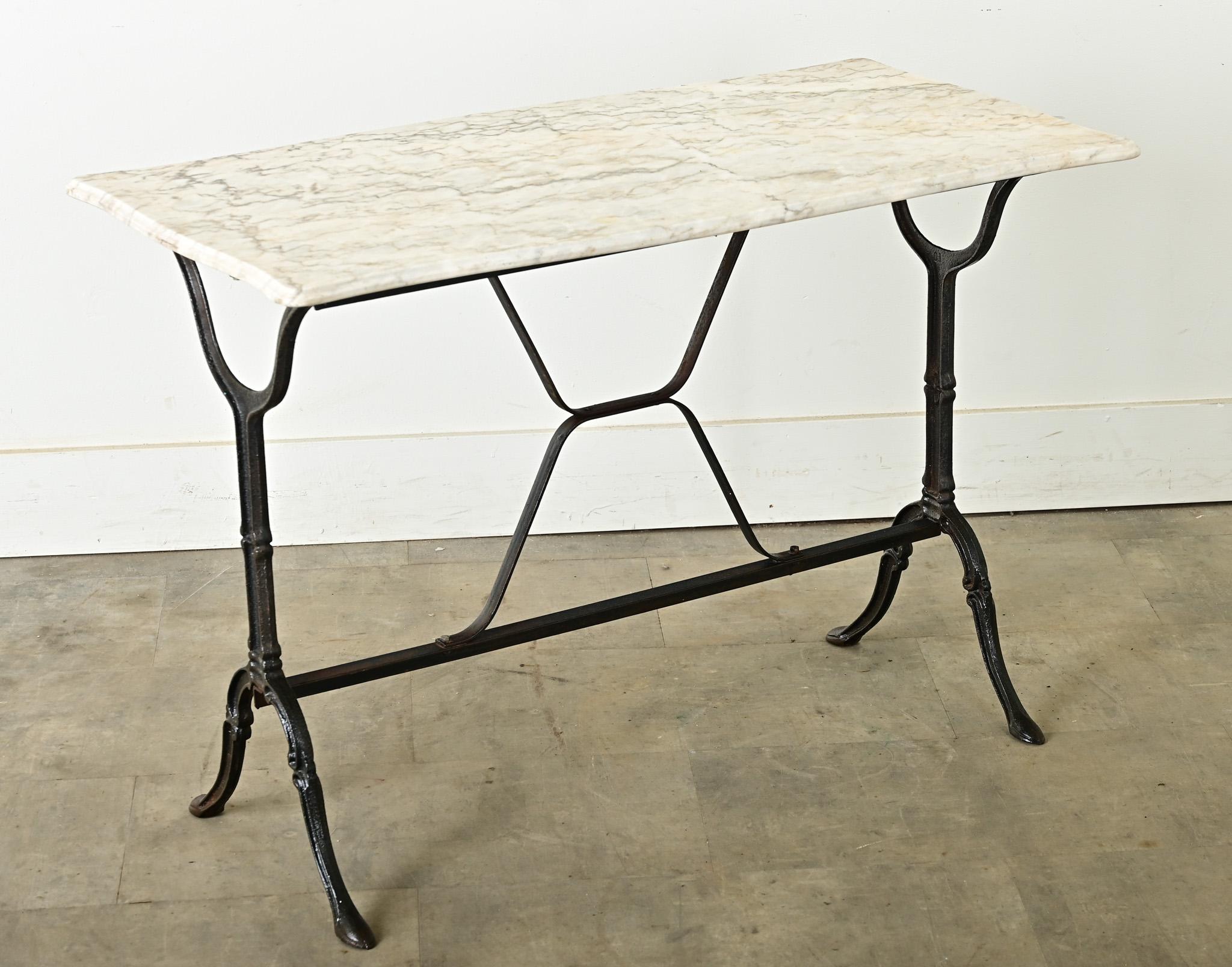A whimsical turn of the 20th century (circa 1900) French bistro table with sensual, Art Nouveau references in the curvaceous silhouette. The white marble slab has a well-patinated surface, etched and clouded over the figurative gray veining of the