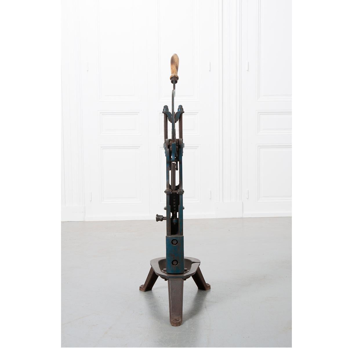 Cast iron bottle corking machine. This model would look wonderful when placed on a workbench and still has some of its original paint. Column with guides and counterweight on chain. Long lever in the shape of a question mark. Round wooden block on