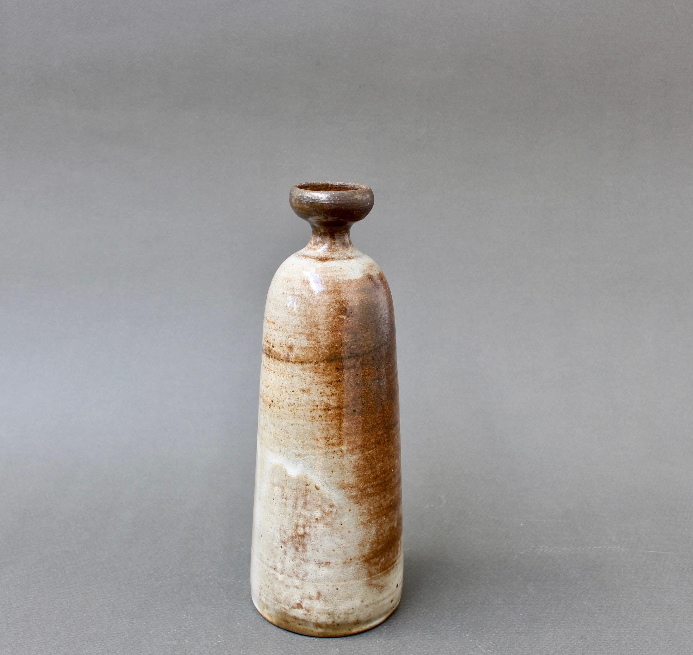 Mid-century ceramic vase by Jacques Pouchain / Atelier Dieulefit (circa 1960s). Classically bottle-shaped vase with elegant mouth in Pouchain's signature cloudy glaze style with earth tone hues. It is elegant with a multi-hued surface in dark brown