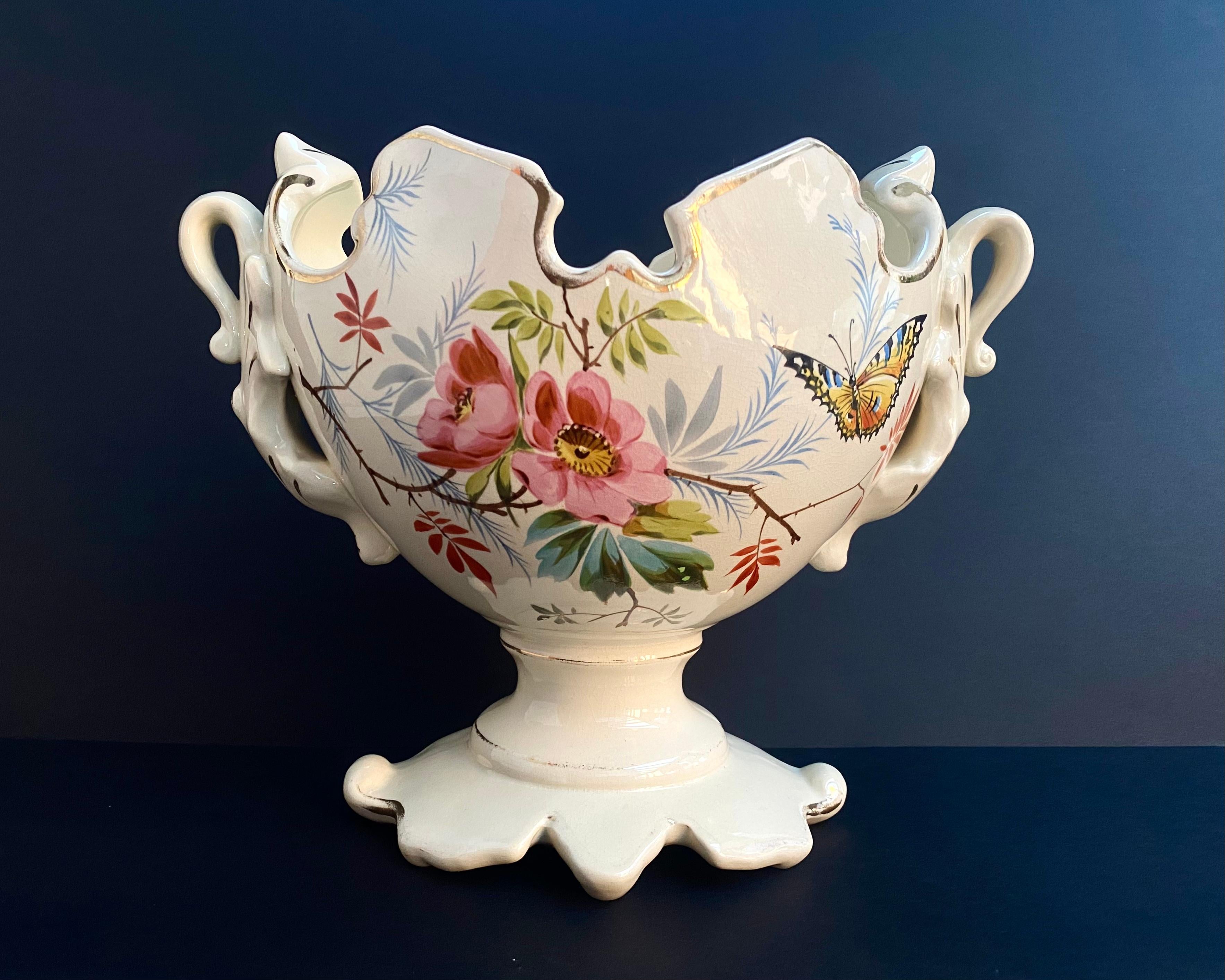 Large Vintage ceramic French planter, centerpiece, Regency style, hand painted with flowers and a butterfly, circa 1950.

Beautiful hand painted flower design on an off-white cream colored base with golden rims, has swan-like handles and sculpted