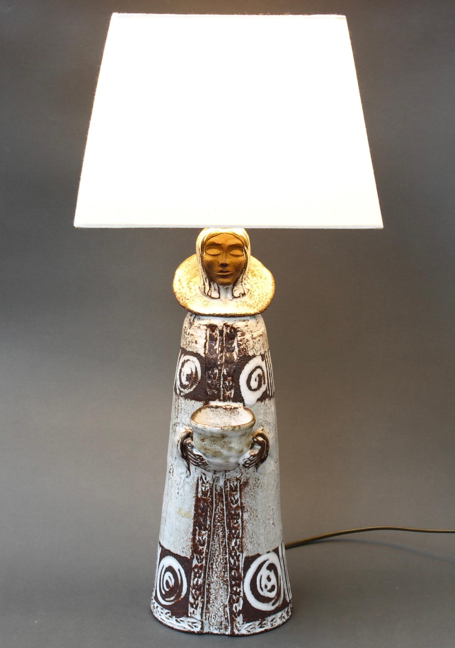 Lampe de table en céramique vintage française par Albert Thiry (circa 1970). Le céramiste Thiry a créé ce personnage - un clerc debout - qui porte un collier à l'ancienne et dont les mains sortent de la robe pour tenir une sorte de récipient